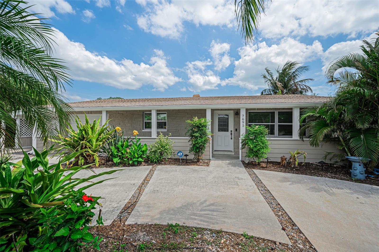 Positioned on a corner lot just moments from the shoreline, this thoughtfully renovated St. Pete Beach residence captures an effortless coastal lifestyle, where a short walk or golf cart ride leads to the Gulf’s sugar sand beaches and the shops and dining along Corey Avenue. A welcoming front porch sets the tone, offering a relaxed introduction to a home designed for easy, everyday living. Inside, natural light fills the space, highlighting polished terrazzo floors that run throughout and create a clean, cohesive aesthetic. The living room flows seamlessly into the kitchen, offering an open yet comfortable layout suited for both daily living and casual entertaining. The kitchen is finished with white shaker-style cabinetry, granite countertops that extend up the backsplash, and a full suite of appliances. Just beyond, sliding glass doors open to a fully enclosed and air-conditioned Florida room, creating an additional living space that transitions effortlessly to the outdoors. The primary suite offers a comfortable retreat with a freshly updated en-suite bath featuring a walk-in shower and modern finishes. A guest bedroom is complemented by an updated second bath with a tub/shower combination and coastal-inspired details. Thoughtful storage is found throughout. Outdoors, a private pavered pool area provides a low-maintenance setting ideal for relaxing or entertaining, complete with an outdoor shower and detached shed for beach and seasonal storage. Recent upgrades include a 2019 roof with hurricane ties, energy-efficient windows (2022), a 200-amp electrical panel with EV charging, tankless water heater, updated HVAC, and a resurfaced pool. Ample parking is thoughtfully integrated with a one-car garage, a deep carport with electric vehicle charging, and a circular driveway that allows for easy access and guest accommodations. Set within one of St. Pete Beach’s most desirable and walkable locations, this home offers the ability to move effortlessly between beach days, sunset dinners, and vibrant local gathering spots, delivering a lifestyle that feels both relaxed and intentionally curated.