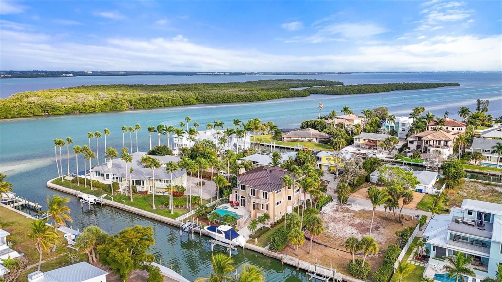 NOW OFFERED WITH A SIGNIFICANT PRICE IMPROVEMENT, 761 Norton Street presents an exceptional opportunity to own a luxury waterfront home in Longboat Key's highly desirable Sleepy Lagoon community. Positioned along a quiet canal with direct boating access to Sarasota Bay, the Intracoastal Waterway, and the Gulf, this canal-front residence combines the durability of reinforced concrete construction with the relaxed sophistication of Florida waterfront living. Featuring four bedrooms, four full en-suite baths, three half baths, and 4,674 square feet under air, the residence was thoughtfully designed to accommodate multi-generational living, extended family visits, seasonal guests, or those seeking exceptional flexibility for entertaining. Built with enduring quality in mind, the home features solid poured concrete construction reinforced with rebar throughout, hurricane-rated windows and doors, and a five-stop elevator providing convenient access to every level. A light-filled travertine foyer with an interior water feature creates a memorable arrival, while smart-home technology and newly installed remote-controlled blinds add modern convenience throughout. The main living level centers around an open-concept kitchen and gathering space designed for effortless indoor-outdoor living. Custom wood cabinetry, stainless steel KitchenAid appliances, a cooktop, beverage cooler, and generous entertaining areas flow seamlessly to the outdoor terrace. Beyond the walls of glass, a private resort-style environment awaits. The travertine pool deck features an infinity-edge pool and spa, outdoor shower, summer kitchen, and Coyote grill, creating an ideal setting for waterfront entertaining and year-round enjoyment. For boating enthusiasts, the property's canal-front setting is among its most compelling features. A 28,000-pound boat lift and dedicated lift for two personal watercraft provide convenient access to the region's renowned boating waters, allowing owners to cruise directly to waterfront restaurants, explore Sarasota Bay, spend the day fishing, or enjoy sunset excursions throughout Longboat Key and Sarasota's barrier islands. Inside, architectural details add warmth and character, including a two-tone tray ceiling, travertine fireplace, custom art niches, and generously sized guest suites with walk-in closets and private baths. One suite features a Jacuzzi tub, dual vanities, walk-in shower, and private water closet with bidet, while additional suites provide comfortable accommodations for family and guests. A rare and distinctive feature of the residence is its mirrored floor plan concept, creating two separate yet connected living experiences under one roof. An additional living level includes a second kitchen, bar area, living room, and matching guest accommodations, offering remarkable flexibility for private guest quarters, extended family living, or long-term visitors. Additional highlights include a 4-car tandem garage, abundant storage, and a premier location on Longboat Key. Residents enjoy convenient access to St. Armand's Circle, the St. Regis Longboat Key Resort, downtown Sarasota, Anna Maria Island, championship golf, world-class dining, boutique shopping, and the area's renowned Gulf beaches. Combining direct boating access, exceptional construction quality, resort-inspired outdoor living, and a coveted Longboat Key location, 761 Norton Street represents a rare opportunity to experience the very best of Florida waterfront living.