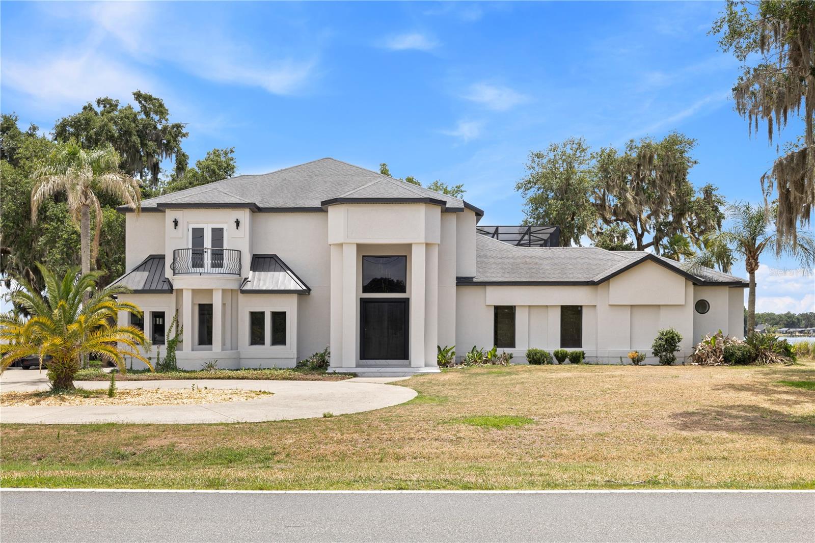 Stunning lakefront estate on the Clermont Chain of Lakes with direct frontage on Lake Minneola in the sought-after Palisades community. This impressive 5-bedroom, 5.5-bath pool home offers thoughtfully designed living space with panoramic water views, refined finishes, and exceptional indoor-outdoor living. An oversized driveway, beautifully maintained landscaping, and custom entry door create a striking first impression. Inside, the grand foyer showcases dramatic flooring, soaring ceilings, designer lighting, and professionally selected finishes that blend modern elegance with warm contemporary style. Expansive living spaces feature custom wall details, built-in lighting, and seamless views of the pool area and lakefront setting. The gourmet kitchen is designed for both everyday living and entertaining, featuring granite countertops, custom wood cabinetry, double ovens, modern appliances, abundant storage, a spacious pantry, and an open-concept layout overlooking the water. The combination of natural wood tones, carefully selected stone surfaces, and custom lighting creates an inviting atmosphere. The first-floor primary suite offers a private retreat with lake views, sitting area or office space, oversized custom closets, dual vanities, Victorian, spacious walk-in shower, and spa-inspired finishes. Upstairs includes additional bedrooms, flexible media or recreation space, balcony access, and water views from multiple rooms. Outdoor living is equally impressive with a screened pool and spa, covered entertaining areas, and a private double-decker dock designed for enjoying the waterfront lifestyle. The dock includes boat slips, lift access, upper-level gathering space, and direct access to boating, fishing, skiing, and other water activities on the Clermont Chain of Lakes. Additional highlights include high ceilings, sliding doors, irrigation system, modern laundry room, attached garage, and updated major systems. Conveniently located near shopping, dining, schools, and major roadways while offering the privacy and lifestyle of luxury lakefront living.