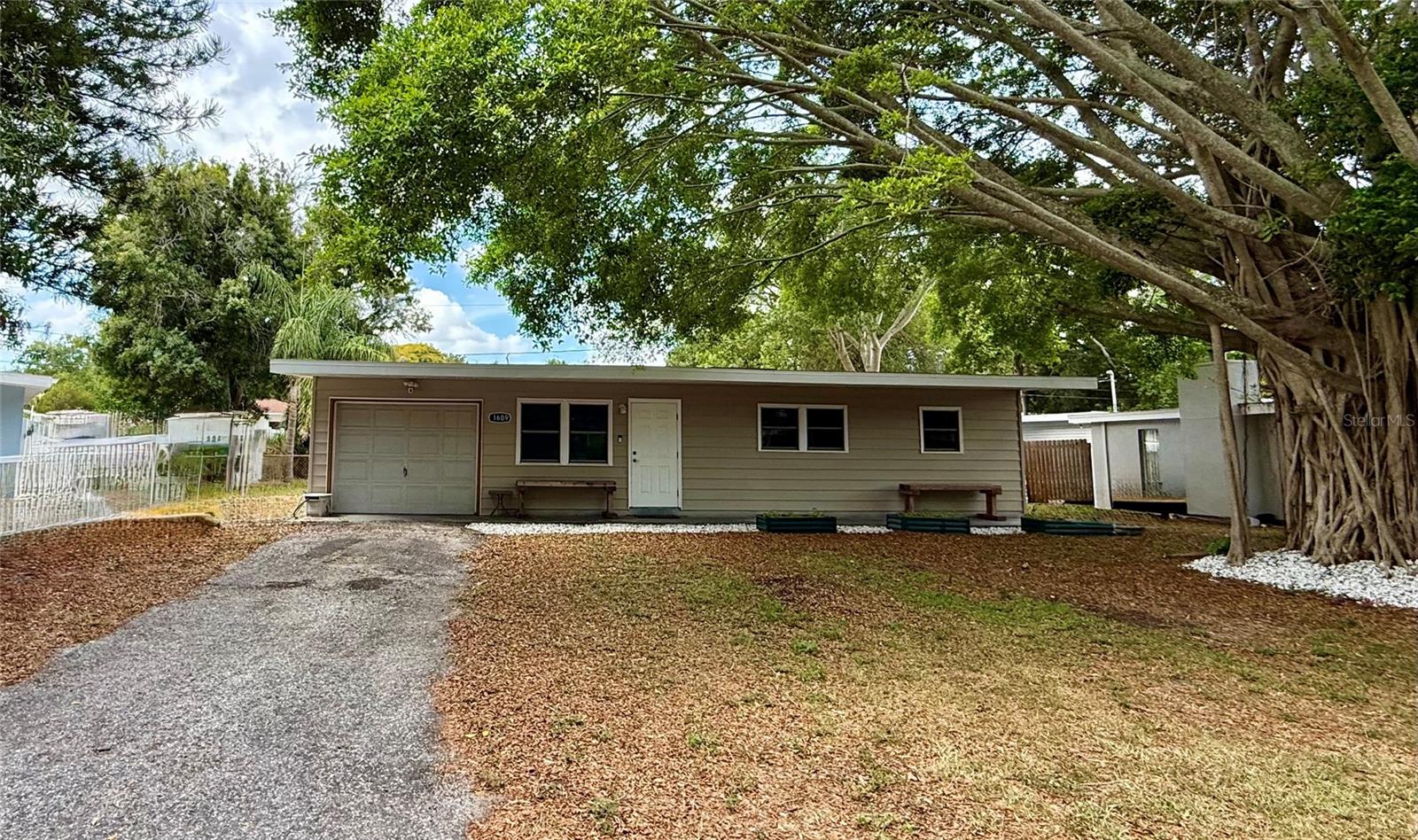 **IN THE HEART OF CLEARWATER** Charming two bedroom ranch style with an open concept floor plan designed to entertain! Huge Chef's kitchen with sleek black and gold flake quartz countertops, custom wood cabinets, deep under mount sink, bold 16" tile flooring, built in microwave, lots of counter and cabinet space. Gleaming wood laminate floors, soaring textured ceiling and walls, decorative baseboards and door frames, half circle archway, ceiling fans with light fixtures, whole house water softener system, large linen closet with ornamental lead glass door and popular barn style sliding door. Spacious primary suite and second bedroom. Bathroom has an updated bright white vanity, tile surround and a tub/shower combo. Quality updated Simonton Energy Star Certified tempered glass double hung thermal pane windows and PGT doors. Enormous screened outdoor living area overlooking the huge fenced in backyard. A Gardner and Plant enthusiant dream come true! Enjoy growing what you love in your very own oversized walk in tunnel greenhouse! The greenhouse has brought a lot of joy and happiness to the owner by sharing his beautiful brilliant colored plants and organic vegetables with family and friends. The backyard provides a wonderful outdoor kitchen, complete with a grill, prep station, and sink, fire pit, and lots of space for children and fur babies. Additionally, the backyard includes many raised flower beds for your planting pleasures. Large covered front porch with a great view of your Iconic Banyan Tree. One car garage with work bench, side service door to exterior, full size LG washer and Dryer remain. New roof (2022) Durable Trane XR AC (2018) Rheem water heater (2021) High and dry flood zone X. NO HOA! Easy access to St. Petersburg, Tampa, major highways and interstates and OUR WORLD FAMOUS SUGAR SAND BEACHES! Call and schedule your private showing and make this your FLORIDA HOME TODAY!
