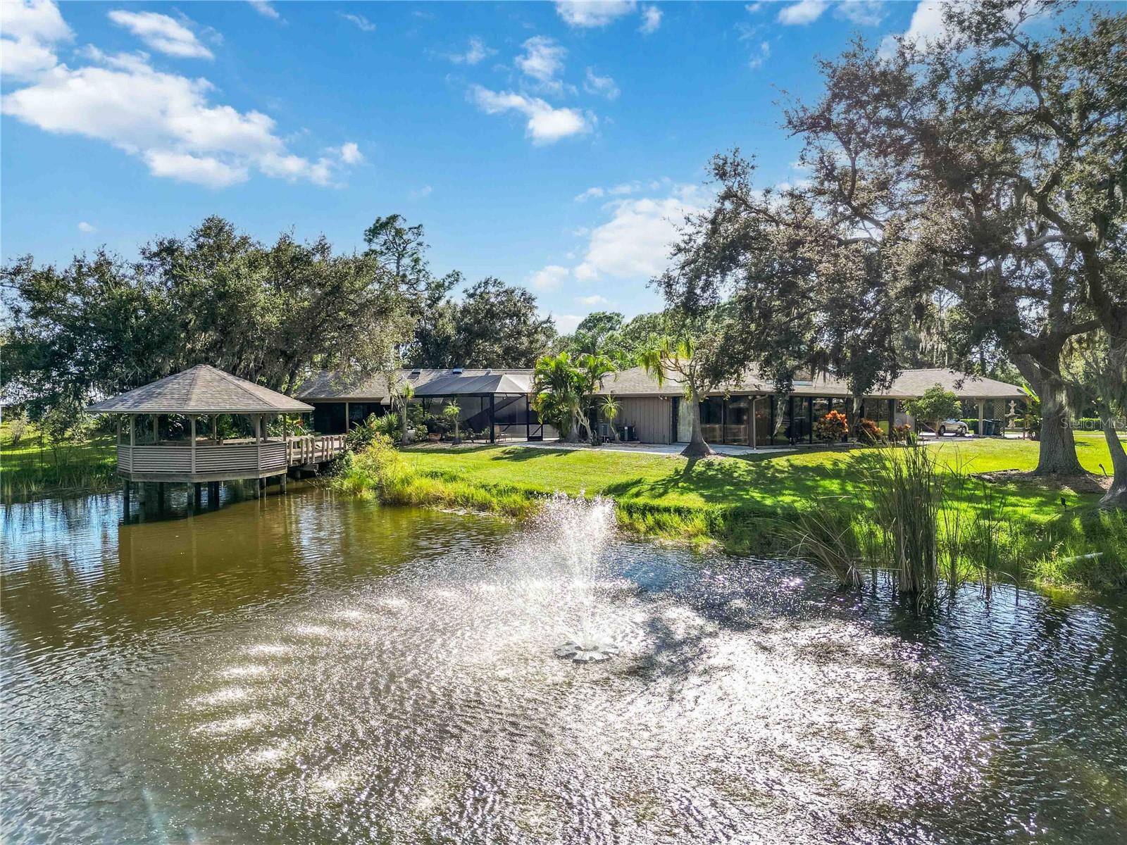 A truly rare opportunity to own a home on over 2 acres in Osprey, FL. Pine Ranch is a charming enclave of 36 properties with low HOA fees and sensible deed restrictions that offers room for your RV, boat, and space for your horses.

Conveniently positioned one mile East of US 41, within a mile of the Legacy Trail and the nationally-ranked Pine View School. Situated at the end of a cul-de-sac and bordering a protected preserve, this property offers privacy almost impossible to find West of I75 in Sarasota County. From nearly every window in the home, enjoy the views of the surrounding nature, a private fish-stocked pond, picturesque gazebo, and well-appointed pool area.

Improvements in 2025 include a new hot water heater, picture frame pool enclosure, and roof with transferable warranty. A thoughtfully designed addition expanded the original home adding a spacious primary suite featuring a vaulted ceiling, abundant natural light from multiple skylights, dual walk-in closets, a full ensuite bath, and direct access to an outdoor living space with wet bar and pool access. A beautiful library with custom wooden shelves and vaulted ceilings with a full pool bath too.

This home has a total of four bedrooms, two with ensuite bathrooms, all with sizable walk-in closets and four and a half baths. A formal living and dining room, eat in family room with a wood burning fireplace, wet bar and vaulted pecky cypress ceiling and walls, all add up to a great home to gather. The home also boasts a converted garage space which adds an additional air conditioned 500 square feet, plus a glass enclosed Florida room 555 square feet, these two areas add over 1,000 living square feet not included in the county records. Outside there is a large screened patio to truly enjoy the garden views, four car covered carport, free standing Barn/Workshop with garage door access and attached screened potting shed and a defunct pump house that could become a man cave or she shed!
