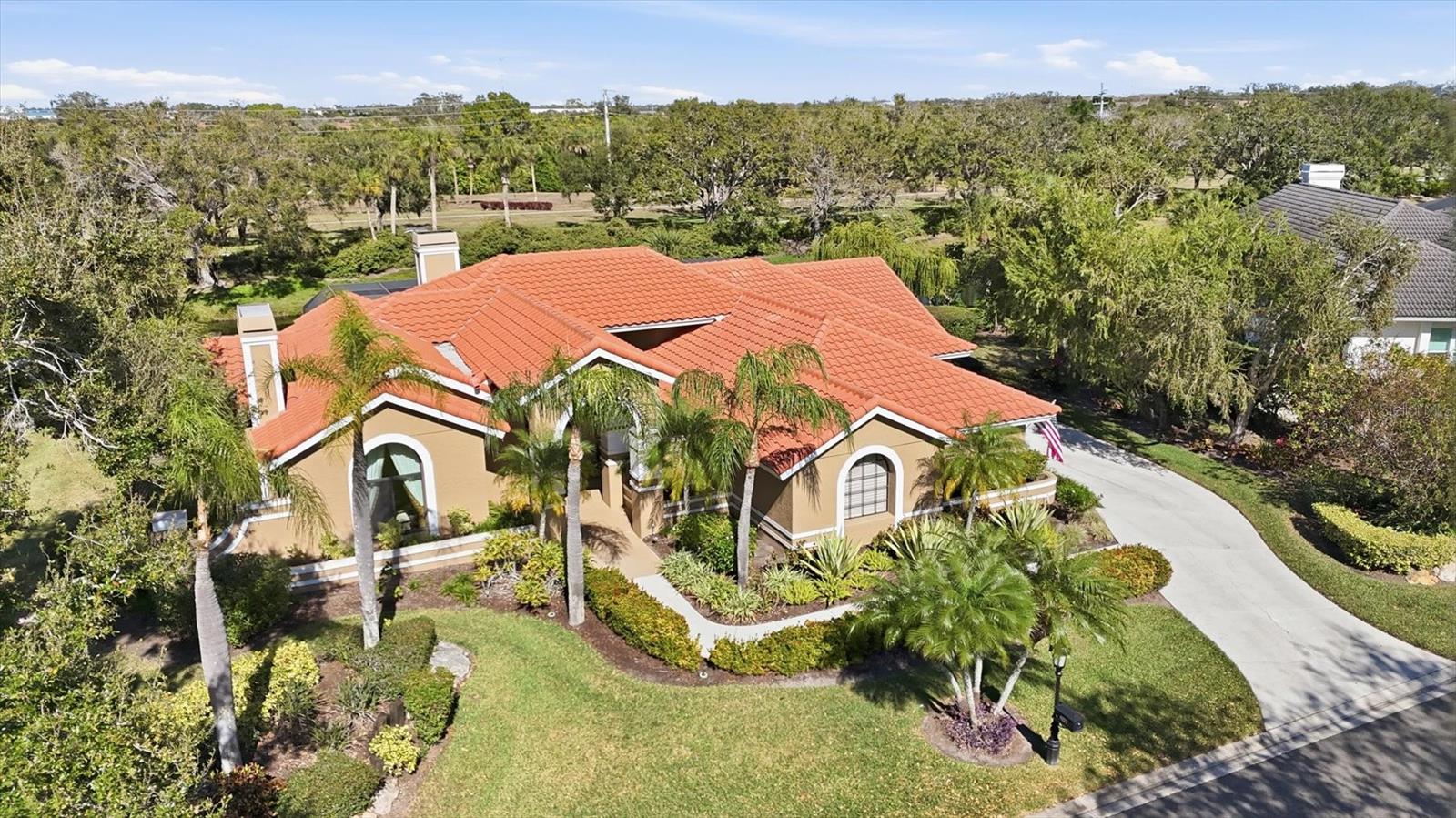 Tucked within the gated Prestancia golf community, 4221 Escondito Circle offers three bedrooms, two-and-a-half baths, and nearly 3,000 square feet of thoughtfully designed living space that blends architectural character with effortless indoor–outdoor living. Lush, mature landscaping lines the graceful walkway to double front doors, while a private side courtyard with a tranquil water feature creates a peaceful sense of arrival before stepping inside. The foyer opens to expansive living spaces framed by soaring vaulted ceilings, arched transitions, and a striking chandelier, with multiple windows drawing in soft natural light and views of the courtyard. The living room feels both grand and inviting, anchored by a wood-burning fireplace with marble and wood detailing and framed by large arched windows. Beyond, the family room offers a second fireplace, custom built-in shelving with lower cabinetry, and walls of glass that connect seamlessly to the lanai. Sliding doors and transom windows fill the space with light while creating an easy indoor–outdoor flow ideal for everyday living and entertaining. At the heart of the home, the kitchen blends warmth and functionality with rich cherry cabinetry, granite countertops, professional-grade appliances, and generous bar seating for six. Five recessed display niches crown the cabinetry, adding architectural interest, while a built-in desk and pantry storage enhance everyday convenience. A pocket door leads to the formal dining room, where vaulted ceilings, a chandelier, and courtyard-facing windows create an elegant setting for gatherings. Adjacent to the kitchen, the breakfast nook is wrapped in picture windows and dual sliders, offering panoramic views of the pool and pond on three sides. The primary suite is thoughtfully positioned for privacy, featuring vaulted ceilings, serene pond views through plantation-shuttered windows, and direct lanai access. A charming bump-out provides space for a desk or sitting area, while the spa-inspired bath offers a glass-enclosed shower with multi-function panel, a corner Jacuzzi tub with marble surround beneath a chandelier, custom cabinetry, and a generous walk-in closet with built-ins. Two additional vaulted bedrooms share a Jack-and-Jill bath with a tub-shower combination and decorative tilework, and one bedroom opens directly to the lanai. A convenient powder room, well-appointed laundry with cabinetry and utility sink, and an oversized two-car garage with epoxy floors and built-in storage complete the interior. Outside, the screened lanai becomes a natural extension of the living space, featuring stamped concrete decking, brick coping, multiple seating areas, ceiling fans, and a hot tub alongside the private pool. Tranquil pond views provide a picturesque backdrop, creating a setting equally suited for quiet mornings or relaxed evenings with friends. Located in Palmer Ranch within Prestancia, residents enjoy a gated lifestyle near TPC Prestancia’s two championship golf courses, with optional memberships available. Just 5.5 miles from Siesta Key Beach and minutes from Sarasota’s dining, shopping, the Legacy Trail and cultural attractions.