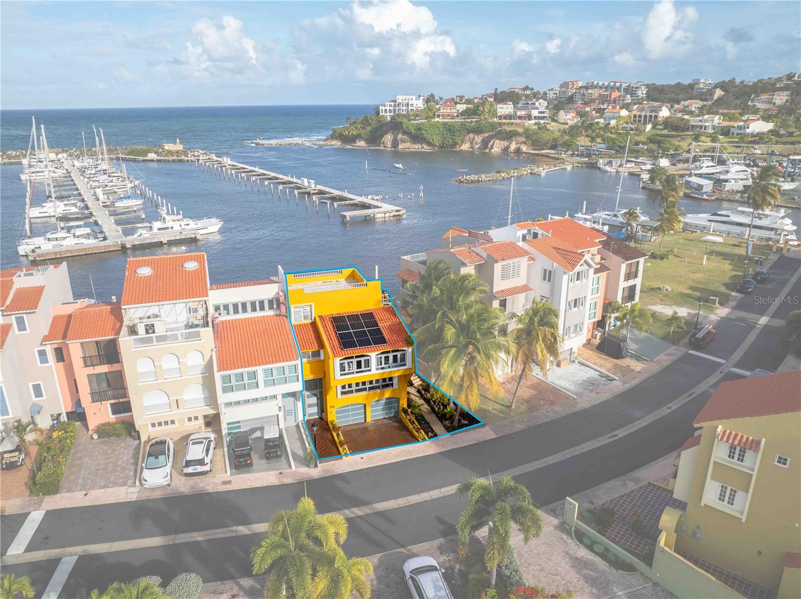 Is there a waterfront home in Palmas del Mar with a private boat slip, pool, rooftop terrace, and resort-style amenities? This split-level residence in Isla San Miguel offers marina views, modern indoor-outdoor living, a 50-foot private boat slip, solar system, equipped interiors, and access to the gated Palmas lifestyle in Humacao, Puerto Rico.

Located within the gated Isla San Miguel enclave of Palmas del Mar, this spectacular waterfront home is designed for boating, entertaining, and relaxed coastal living. A welcoming entry opens to a lower level with a full bathroom conveniently positioned near the garage entry, ideal after time by the pool, boat, or beach.

A short flight up, the dramatic two-story living room showcases soaring ceilings, expansive windows, beautiful natural light, and direct access to the patio, pool, deck, and water views. The open-concept kitchen and dining area continue the waterfront experience with a modern center island, wine cooler, under-cabinet lighting, and large sliding doors that connect seamlessly to the outdoor entertaining areas.

Highlights include:

• Private 50-foot boat slip directly at the residence
• Backyard pool, heated spa, deck, and compact outdoor kitchen
• Open modern island kitchen with waterfront views
• Dramatic high ceilings and abundant windows
• Loft with custom curved railing overlooking the living room
• Primary suite with private balcony and water views
• Secondary bedrooms with impressive views and flexible layout
• Rooftop terrace with 360-degree marina, ocean, and coastal views
• Full laundry room with sink
• Solar system and sold equipped for convenience
• Located in Isla San Miguel within Palmas del Mar

The upper levels provide privacy and flexibility, including a guest suite with en-suite bath and walk-in closet, a large secondary bedroom with balcony, and a dedicated office nook. The private primary suite offers a viewing balcony and spacious bath with soaking tub, separate shower, double vanity, and direct water views.

This waterfront home in Palmas del Mar places you in one of Puerto Rico’s premier resort communities, with 24/7 gated security, golf-cart-friendly living, two championship golf courses, tennis and pickleball facilities, an equestrian center, yacht club marina, restaurants, and miles of coastline moments from home.