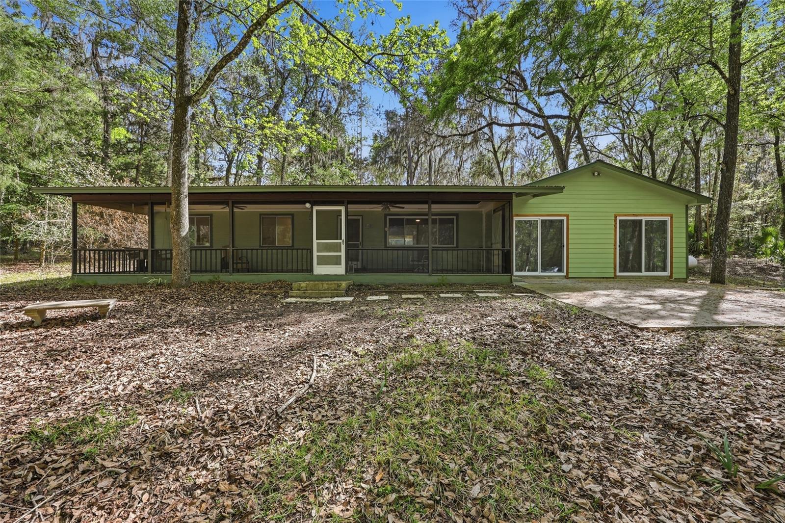 Own your own slice of Florida paradise on 6.83 acres in Micanopy, where the only neighbors in sight are the local deer and your home has been fully renovated with high-end finishes throughout 2,163 square feet of heated living space. From the moment you turn off the paved road and onto the winding gravel driveway, the curb appeal is immediate—defined by the majestic beauty of a dense canopy that provides a natural barrier from the outside world. The residence greets you with an expansive, screened-in front porch that extends along most of the home’s length, offering a quintessential space to enjoy the outdoors. Step inside to a layout that has been thoughtfully transformed, including a converted garage that now serves as a massive, light-filled living area featuring wide-plank LVP flooring, a new textured ceiling with LED lighting, and updated sliding doors. For the culinary enthusiast, the updated kitchen is a showstopper, boasting gleaming quartz countertops, new cabinetry, under-cabinet lighting, and consistent flooring that flows into the formal dining and living spaces. The interior is further highlighted by a unique primary suite, created by combining two smaller rooms into one grand, functional retreat featuring dual ceiling fans and "his and her" closets with bifold doors. This transition has evolved the home into a spacious two-bed, three-bath layout where every bathroom has been touched, including a fully updated guest bath with a walk-in tile shower and a well-maintained second bath featuring beautiful tile and a modern vanity. Modern mechanical upgrades provide ultimate peace of mind, including a new 5-ton AC unit, a whole-home generator with a propane tank, and recent roofing repairs with new plywood sheeting and fascia boards. The transition to outdoor living is seamless via a dedicated laundry and mudroom—where the washer and dryer convey—leading out to a back patio area designed for tranquility. The backyard is a vast, natural expanse featuring a French drain system to manage runoff and a substantial metal workshop building with a garage door, offering a major benefit for any hobbyist. Located in a quiet, no-HOA community on the Marion County side of Micanopy, you enjoy the benefit of lower property taxes while remaining just minutes from the "town that time forgot." Whether you are wandering through historic Micanopy’s antique shops or making the short drive to Gainesville for premier medical facilities and the University of Florida, this 6.83-acre legacy offers the ultimate balance of secluded homesteading and modern convenience. Schedule your private tour today to experience this one-of-a-kind woodland property in person before it is gone!
