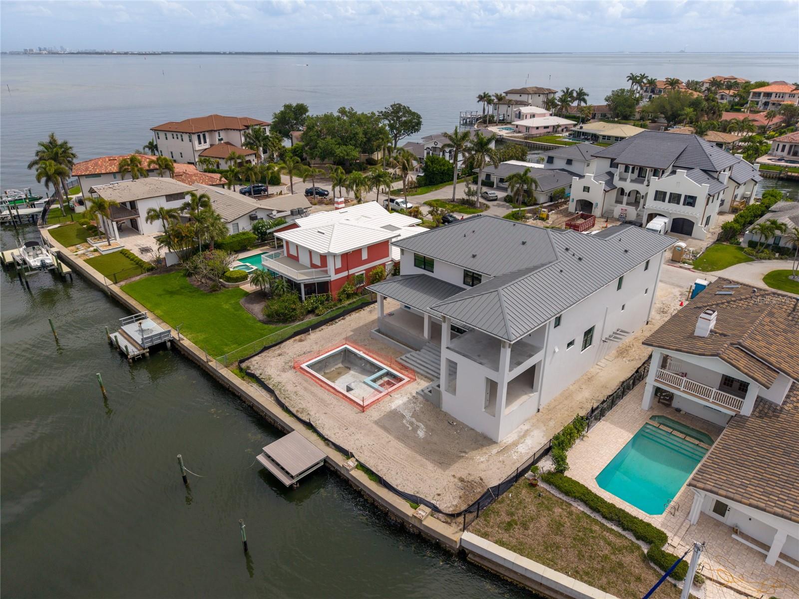 Under contract-accepting backup offers. Under Construction. Experience the pinnacle of waterfront living in Venetian Isles, one of St. Petersburg’s most coveted waterfront communities. MINU Homes is redefining new construction with this masterful estate, where architectural foresight meets unparalleled material quality. Situated on a rare, oversized 11,430-square-foot lot, this residence offers the ultimate luxury: a sprawling interior footprint without compromising on outdoor paradise with a sparkling pool and coveted green space. 4,555 square feet of indoor living with 4 bedrooms, each with 4 ensuite bathrooms, plus a media room/den, powder bathroom, 2 utility rooms, elevator shaft, 3+car garage, and over 900 square feet of covered outdoor living. Exquisite Craftsmanship & Design Built with solid block construction on both levels and finished with smooth Level 5 walls, the structural integrity is matched only by its aesthetic detail. The open-concept floor plan features soaring 10-foot ceilings accented by wood beams and custom millwork. The chef’s kitchen is a culinary masterpiece, featuring a Wolf gas range, Sub-Zero refrigeration, Cove dishwasher, and a hidden walk-in pantry equipped with a beverage cooler and ice maker. Seamless Indoor-Outdoor Living Designed to capture breathtaking vistas of the Weedon Island Preserve and the evening glow of the Gandy Bridge, the home sits "high and dry" above required elevations. Retract the pocketing slider doors to an expansive patio featuring a full outdoor kitchen, fireplace, and dining area—all overlooking a custom pool, spa, and lush green space. The Private Retreats, located on the second level, are a sanctuary of comfort. Every bedroom features a private en-suite and spacious walk-in closet. The primary suite is a true escape, boasting tray ceilings, a private balcony, a morning coffee station, and a spa-like bath with a free-standing soaking tub. For entertainment, the dedicated media room is movie-ready with integrated AV storage and a refreshment center complete with a microwave and beverage cooler. Come experience the Best of  Waterfront Lifestyle St Petersburg has to offer. Located on a deep-water canal with unobstructed access to Tampa Bay, this home is a boater's dream. Enjoy the quintessential St. Pete lifestyle: golf cart to Downtown, quick access to top-rated schools, or a short trip to Albert Whitted Airport for a weekend getaway. Easy access to Tampa and our world-famous beaches.  This home is scheduled to be completed June 2026