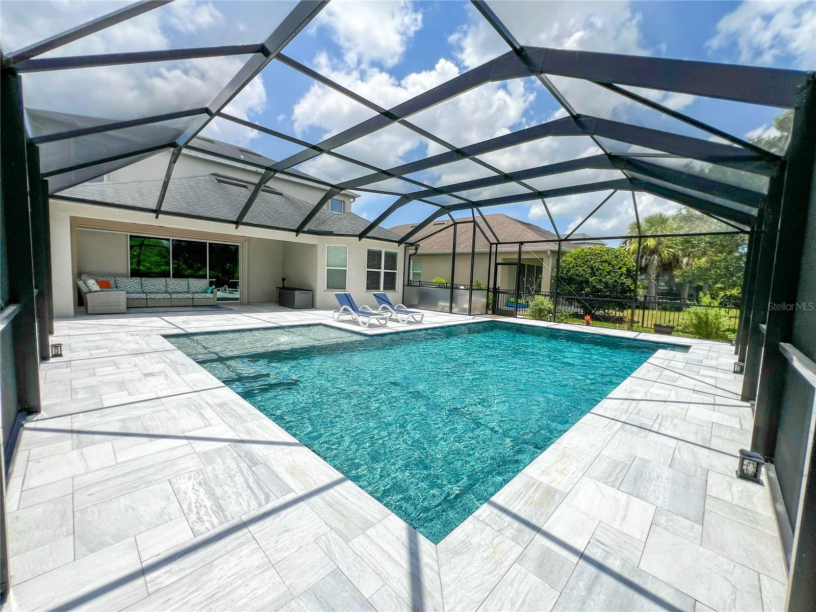 Welcome to this exceptional residence built in 2019, nestled within an exclusive gated community. This impressive two-story home features 4 bedrooms, 3.5 bathrooms, a spacious loft, and a 2-car garage, all enhanced with high-end finishes. Newly completed in 2025, the breathtaking over the top custom pool, expansive patio, and panoramic screened birdcage enclosure overlooks a scenic conservation area. The elegant glass entry door with decorative sidelights and a transom window creates a grand first impression. Step inside to soaring ceilings, beautiful tile flooring, rich wood stair railings accented by crisp white balusters, and an abundance of natural light that immediately showcases the home's open and airy design. Just off the foyer, the formal dining room is highlighted by a custom chandelier and oversized windows, creating an elegant setting. Continuing into the heart of the home, the chef's kitchen is designed to impress with custom cabinetry, gleaming quartz countertops, stainless steel appliances, a built-in wall oven and microwave combination, glass cooktop, designer vent hood, recessed lighting, oversized walk-in pantry, and an expansive island complete with seating, electrical, and generous storage. The spacious family room is centered around a custom recessed entertainment wall, while oversized pocket sliding glass doors open to a private resort-style backyard retreat. The covered lanai features dual ceiling fans, recessed lighting, and the amazing custom pool deck. A motorized hurricane screen for the pocket sliders provides added convenience and protection without sacrificing the breathtaking views. Privately situated on the first floor, the owner's suite offers a tranquil escape featuring a recessed tray ceiling accented with crown molding, a bay window that fills the room with natural light, luxury laminate flooring, a ceiling fan, and two spacious walk-in closets with custom organization. The owner's bath offers granite-topped dual vanities, decorative lighting, an oversized walk-in shower, a relaxing soaking tub, and a private water closet. The first floor is completed by a powder bath and a mudroom just inside the garage, featuring custom built-in cabinetry, granite countertops, and a sitting bench for convenience. The oversized garage itself has been finished with durable epoxy flooring and is complemented by an automated irrigation system serving the home's professionally maintained landscaping. Upstairs, an expansive loft with four oversized windows offers endless possibilities as a media room, executive home office, fitness area, or game room. Nearby, the conveniently located laundry room includes built-in shelving for added organization, while an oversized linen closet provides exceptional storage. Three generously sized guest bedrooms offer comfort and privacy. One bedroom enjoys its own private en-suite bath complete with granite countertops, decorative lighting, a tub and shower combination, and a walk-in closet. The remaining two bedrooms are connected by a beautifully appointed Jack-and-Jill bathroom featuring dual sinks, granite countertops, decorative lighting, and a shared tub and shower. The Tampa Airport, Westfield Citrus Park Mall, Costco, International Mall, less than 4 miles away is the Baybridge Park, upper Tampa Bay Trail/Park, and 30 minutes or less drive to Busch Gardens, Adventure Island, Florida Aquarium, Tampa Riverwalk and our award winning beaches!
