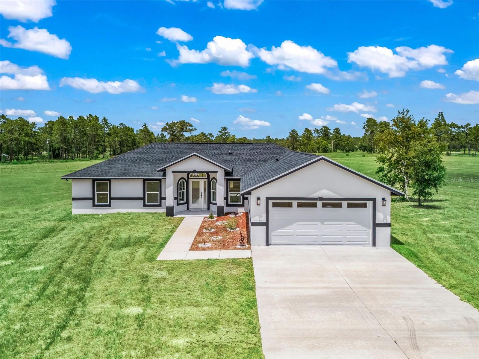 Virtually Staged. Why wait to build when you can move right into this custom home? Situated on a 10 acre lot set back from SE 80th Street for privacy - this estate is fully fenced with a custom gated entryway and is ready for the entire family - including the animals! Completed in 2025, this home offers 2,500 square feet with 3 bedrooms, 2 bathrooms, plus an office. The covered & tiled entryway leads through the decorative leaded glass front door and into the foyer. You will appreciate large marble-look tile flooring that carries throughout the entire home, tall ceilings and plenty of natural light. The kitchen is open to the living space and features soft-close shaker cabinetry with contrasting granite countertops, walk-in pantry, tile backsplash and a suite of stainless steel appliances including French door fridge, smooth glass cooktop with hood, built-in oven and microwave. The primary suite offers access to the lanai, a walk-in and built-in closet, and ensuite bathroom with dual sink granite vanity, walk-in shower complete with rain head, wand and glass enclosure, a standalone garden tub with tile surround and separate water closet. The opposite side of the home offers a dedicated office with double door entry, two additional bedrooms with built-in closets and a shared bathroom with tiled walls, a granite vanity and a tiled walk-in shower with glass door. There is also an indoor laundry room complete with washer and dryer leading to the attached two car garage. The back of the home offers a covered porch overlooking your serene pasture land where you can bring your visions and dreams to life across the sprawling 10 acre lot with barns, stables, workshops, sheds, cross fencing, etc. Please enjoy the attached video and 3D tours, and set up a private viewing of this move-in ready home!