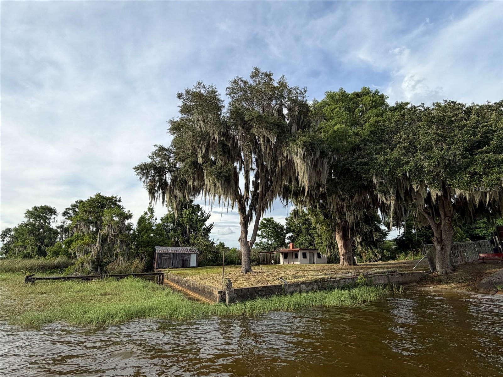 No HOA Located next to Public Boat ramp on Little Lake Harris. Concrete block former fish camp 400 square feet residential building with CONCRETE SEAWALL and dock,  house built in 1948  according to property appraiser records. All block old Florida building. Concrete roof.   Rare find to have your own piece of Old Florida. Old Cypress Boat house and a touch of old Florida History.  Create your own Loveshack on the water, watching the amazing sunsets. Property is being sold as-is where is. Buyer to do their due diligence prior to contract. Sellers will not accept inspection periods or zoning changes. Seller has never occupied property. Located on the Harris Chain of Lakes which takes you to restaurants and destinations on the water.  NO HOA and waterfront.  You have space to possibly park your boat,  seaplane or RV in your yard.  Stillwater Cove community adjacent with amazing new construction homes to purchase and water front lots available to build on.  As Is. Astatula is in the middle of Lake county which allow easy access to most desirable destinations in the county by water or roads. There is no kitchen. This is Florida history in action. No insulation, all concrete block. Please verify parking with county rules and requirements. Harris chain of lakes, consisting of seven lakes that have approximately +/- 13,788 acres