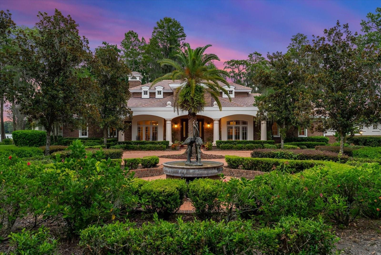 Welcome to your serene retreat on Lake Hiawatha in Odessa. This elegant lakefront estate enjoys 180-degree views of one of the largest private fresh water, spring-fed lakes in Hillsborough County. Truly unique to the area, Lake Hiawatha boasts both its generous size at over 140 acres, as well as two nature preserves on the North and South sides of the lake, ensuring quiet refuge and an abundance of wildlife, including deer, otters, various bird species, bald eagles and bountiful populations of freshwater game fish just to name a few. Two freshwater springs create superior water quality and unmatched water clarity. Tucked behind its privacy gate and private entry driveway lined by beautiful crepe myrtle trees, this spectacular lakefront compound boasts over 5600sf main family home thoughtfully situated on the peninsula providing endless natural light and breathtaking views of the lake and picturesque oak trees, maples, and cypress trees. 
The main house offers a top-of-the-line chef's kitchen with all Viking appliances, warming drawers, granite countertops, an oversized island with additional prep sink, and an intimate wet bar just off the hallway between the kitchen and billiard/seating room. it also features a walk-in pantry, extra refrigerator & freezer adjacent to the oversized laundry room large enough for another office  or designated homework area. Truly unique, come unwind in the   DOWNSTAIRS oversized primary bed and bath with coffered ceilings and large picture windows stunning southern and eastern views of the lake. 
The formal dining, separate living room, and cozy office with views of the lake and a secondary covered patio for enjoying morning coffee. Two generous en-suite bedrooms upstairs also boast views of the lake and a private outdoor seating area. Just off the main home lies a detached 900sf art studio/office/gym with large picture windows overlooking the lake. Towards the front of the property there is an oversized 1300sfworkshop/garage with separate kennels & a chicken coop, along with a recently updated 2br,2ba Old Florida living cottage. At the heart of the property, enjoy an original 1910 cypress wood barn, fully restored in 2017 with cross beams, concrete polished floors, stage and lighting for live music performances, and a fabulous historic bar that runs the length of the barn. What could be better you ask, how about an adjoining outdoor bbq area with brick firepit for large gatherings with family & friends! Come enjoy the the lake views sitting on a newly constructed split-level dock with boat lifts to accommodate a large pontoon boat or ski boat, two jet skis and 2 fishing kayaks or stand-up paddle boards. Designed for entertaining and large gatherings. The property is also home to over 200 flowering trees on the grounds with azalea, gardenia, and flowering bromeliads encircling many of the live oak trees. Thinking of car collecting...bring 8 of your favorite cars to park in one of 3 garages!  Full security cameras around the main home and throughout the grounds. Recent updates include new  large Generac propane generator to power downstairs in 2023,. Concrete tile re-roof in 2017. Termite tent treatment to all outbuildings in 2023. Do not miss the opportunity to own your slice of paradise.