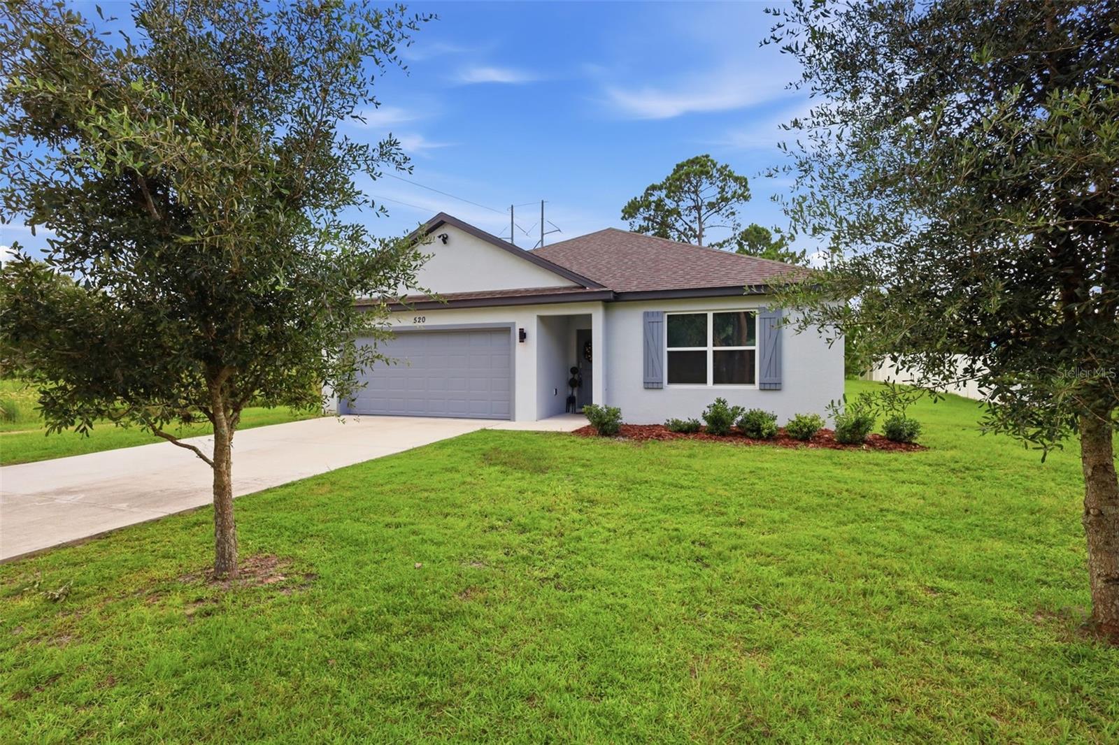 Beautifully maintained and move-in ready, this 2021-built DeLand home offers a clean, modern feel on an OVERSIZED LOT with NO HOA. Inside, the home features 3 bedrooms, 2 bathrooms, approximately 1,560 square feet, and an attached 2-car garage with epoxy floors. The heart of the home is the open-concept kitchen, dining, and living area, creating an easy flow for everyday living and entertaining. The kitchen features white cabinetry with crown molding, stone countertops, stainless steel appliances, pendant lighting, recessed lighting, a large center island with seating, and a clear view into the main living space. Wood-look tile flooring runs throughout the entire home, giving the home a warm but low-maintenance finish. The primary suite offers a comfortable retreat with a walk-in closet and private en-suite bathroom featuring dual vanities and a tub/shower combination. Two additional bedrooms provide flexibility for guests, an office, or hobby space. Out back, sliding glass doors lead to a COVERED REAR PATIO overlooking a spacious backyard, offering room to relax, entertain, garden, or enjoy the extra yard space as the home comes with another parcel of land just being the septic. With a newer construction feel, a functional single-story layout, and a convenient DeLand location near shopping, dining, Downtown DeLand, and outdoor recreation such as Hontoon Island, DeLeon Springs, and Blue Springs State Park, this home is one you will not want to miss. CALL TODAY TO SCHEDULE YOUR PRIVATE SHOWING.