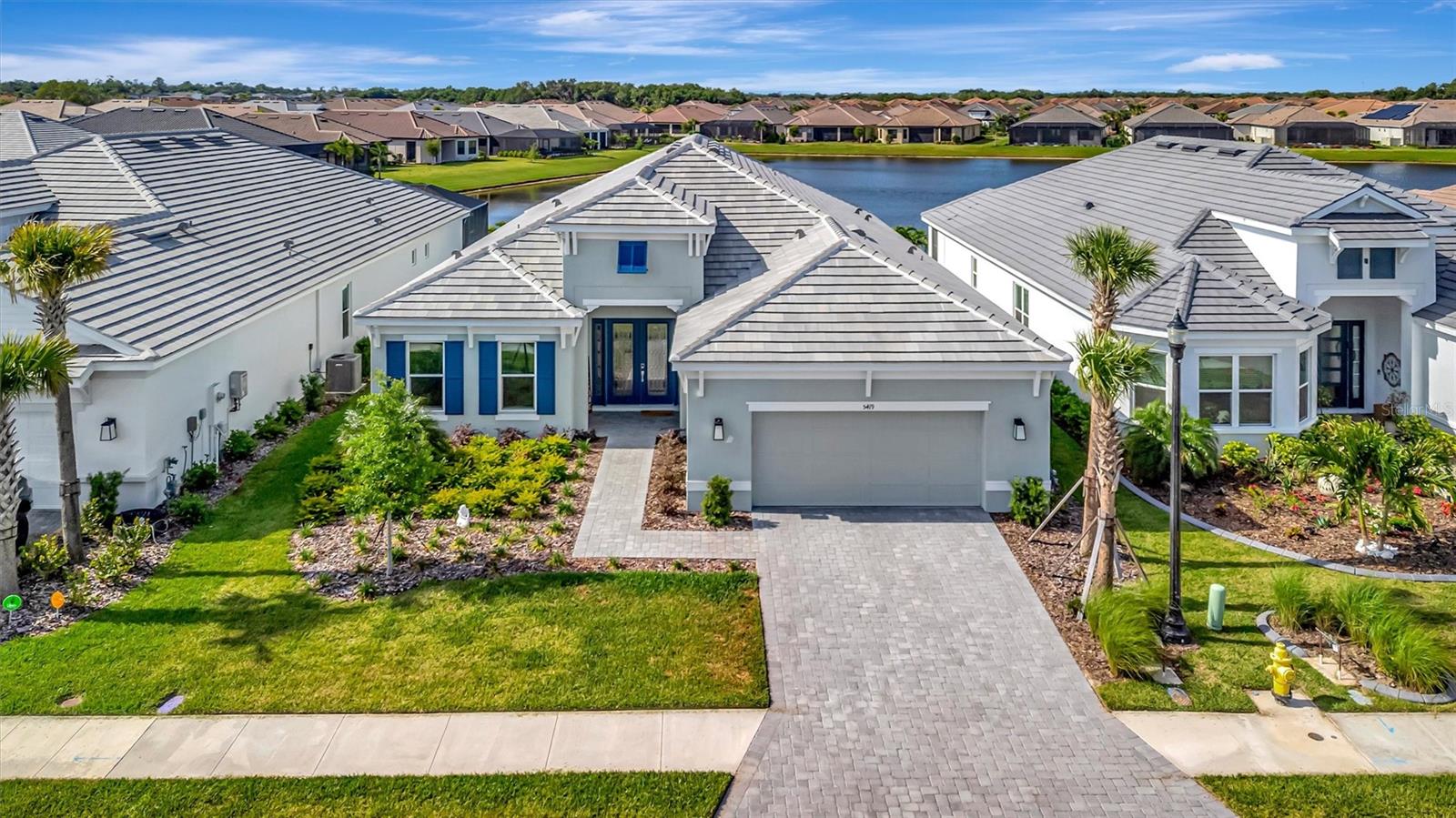 A striking blend of architectural detail, modern design, and tranquil water views defines this exceptional Palazzio model, offering over 3,000 square feet of refined living in one of Palmetto’s most sought after communities. From the moment you enter through the dramatic 12 foot entry with custom picture frame molding, your eye is immediately drawn through the home to the serene water views, creating a stunning first impression that carries throughout the kitchen, living, dining, and primary suite. The heart of the home is the extended chef’s kitchen, thoughtfully designed to balance beauty and function, featuring an expansive quartz island accented by designer pendant lighting, a full height quartz backsplash, GE Café appliances, gas cooking, a wine refrigerator, and reverse osmosis water filtration. This space opens effortlessly into the main living and dining areas, where a statement chandelier defines the dining space and the overall design creates a warm yet sophisticated setting ideal for both everyday living and entertaining. Designed to fully embrace the Florida lifestyle, pocketing sliding glass doors open wide to an extended screened lanai, creating a seamless indoor outdoor living experience enhanced by integrated indoor and outdoor speaker systems. The lanai, finished with brick pavers and a gas fireplace, becomes a natural extension of the living space, perfect for relaxing or entertaining while enjoying the tranquil water views. Hurricane impact windows and doors add both comfort and peace of mind, and the home is located in a non flood zone for added confidence and long term value. Luxury vinyl plank flooring enhances the main living areas, while a thoughtfully designed den or flex room with a shiplap feature wall provides a versatile space for a home office, media room, or private retreat. The owner’s suite is a peaceful sanctuary, positioned to capture water views and offering generous space, a spa inspired bath with dual vanities and walk in shower, and a large walk in closet designed for optimal organization. Bedroom two serves as a private en suite with its own walk in closet, while bedroom three features a pocket door, allowing it to function as a private guest suite with convenient access to a full bath. Additional highlights include a well appointed laundry room with built in cabinetry and a spacious two car tandem garage featuring epoxy flooring and upgraded lighting, with flexible space ideal for exercise equipment or a golf cart in this golf cart friendly community. Located within Esplanade at Artisan Lakes, residents enjoy a true resort style lifestyle with two pools, two clubhouses, fitness facilities, tennis, pickleball, and a vibrant social calendar, all conveniently located near I 75 and within easy reach of Tampa International Airport, Sarasota Bradenton International Airport, and St. Pete Clearwater International Airport, providing exceptional accessibility while maintaining a peaceful, resort style setting. Experience the lifestyle, space, and elevated design this exceptional home offers and schedule your private showing today.