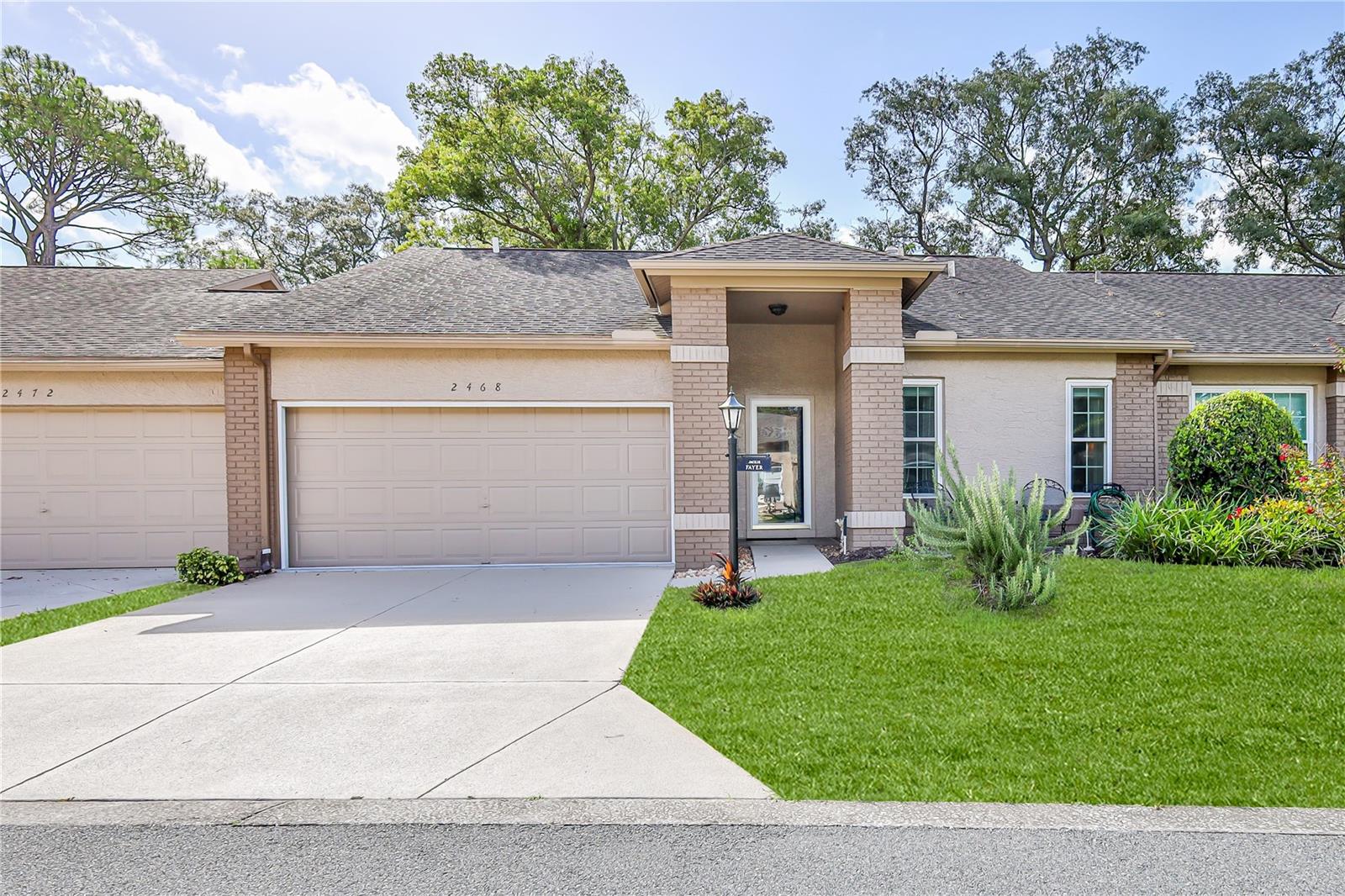 You'll love this beautifully maintained, furnished, 2-bedroom, 2-bath, 2-car garage attached villa offering 1,464 square feet of comfortable living space. Thoughtful updates, quality finishes, and peaceful views make this home move-in ready. Step inside to an inviting living and dining room combination featuring laminate flooring, designer lighting, chair rail, wainscoting, a ceiling fan, and an open layout that flows seamlessly to the enclosed lanai. The bright kitchen overlooks the back yard and features refaced cabinetry with pull-out shelving, stainless steel appliances, recessed lighting, a ceiling fan, tile flooring, a pantry, and a sunny breakfast area. The spacious primary suite offers two large walk-in closets, a ceiling fan, and sliding glass doors leading to the lanai. The updated en-suite bathroom features a dual-sink vanity, solar tube for abundant natural light, beadboard and chair rail accents, and a beautifully tiled walk-in shower with grab bars. The guest bedroom is generously sized with a ceiling fan and ample closet space. The guest bathroom has been tastefully updated with a newer vanity, tile flooring, a full tub with shower, beadboard and chair rail detailing, designer lighting, and a solar tube. Relax on the enclosed lanai with attractive tile flooring, a ceiling fan, and peaceful garden views. Additional features include an inside laundry room with washer, dryer, utility sink, and storage cabinets. The garage includes finished flooring, a workbench, built-in cabinetry, and pull-down attic access for additional storage. Major updates include newer windows, a 2019 HVAC system with a REME HALO® LED whole-home in-duct air purification system, Roof 2010, HWH 2024. Laminate and tile flooring throughout means no carpet to maintain. If you're looking for low-maintenance living with tasteful updates, generous storage, and a tranquil setting, this Whispering Pines villa is ready to welcome you home. Golf cart is included. Maintenance covers exterior painting, irrigation, lawn mowing, front hedge trimming, lawn fertilization, and termite protection - simplifying ownership and freeing up your time. Timber Pines is an award-winning, guard-gated, 55+ community, where residents enjoy three 18-hole golf courses, a 9-hole pitch &putt, 12 pickleball courts, tennis, two community pools, a country club restaurant and bar, fitness center, performing arts, billiards, cable TV, internet, and over 100 social clubs and activities. Located in a no-dog village, this villa offers a peaceful, well-maintained setting with an easy-care lifestyle.