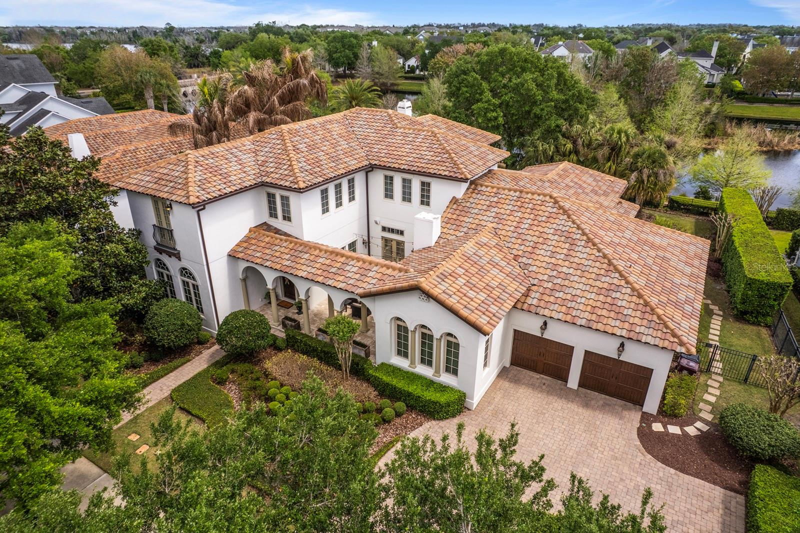 One or more photo(s) has been virtually staged. One of the only large-lot, water-facing estate homes in Baldwin Park, offering a level of privacy, scale, and setting that rarely becomes available. Tucked along one of the neighborhood’s most desirable streets, this Mediterranean-style residence spans over 5,300 SF on more than one-third acre, with tranquil water views and no rear neighbors, creating a true retreat within the heart of the community. A private front courtyard with a gas fireplace provides a warm and inviting setting equally suited for quiet evenings or relaxed gatherings.
Inside, the home balances warmth and sophistication with hardwood and travertine flooring, custom finishes, and natural light pouring in through expansive windows and French doors. The great room anchors the home with a gas fireplace and built-ins, seamlessly connecting indoor and outdoor living.  The kitchen is designed for both everyday living and hosting...featuring marble countertops, custom cabinetry, a full Viking appliance suite, two oversized islands, a walk-in pantry, and a butler’s pantry with dry bar. An adjacent family/media room offers a more relaxed gathering space.  The first-floor primary suite is privately positioned with peaceful pool and water views, a sitting area, and a spa-like bath with soaking tub, walk-in shower, dual vanities, and an oversized custom closet. A secondary bedroom with en-suite bath, dedicated office, laundry room, and pool bath complete the main level.  Upstairs, three additional bedrooms, two with en-suite baths, are complemented by a spacious bonus lounge or retreat with built-in workspace.  Outdoor living is where this home truly shines. A covered, screened lanai with lounge area, dining space, and summer kitchen overlooks a resort-style pool and spa with dual fire features all set against a serene pond backdrop.  Additional highlights include a deep tandem "4-car garage", updated HVAC systems, upgraded electrical, updated plumbing, custom drapery and plantation shutters on all windows, whole-home audio, and full irrigation.  Located in Baldwin Park, this home enjoys a rare position on a quiet, low-traffic street surrounded by other luxury residences, offering a level of privacy and calm that is increasingly hard to find within the community. Just steps away, you’ll find the neighborhood’s vibrant downtown district with its shops, dining, and everyday conveniences, along with scenic trails along Lake Baldwin, community pools, parks, and a fitness center. Ideally situated, the home is also just minutes from Winter Park, Orlando, and both Orlando International Airport and Orlando Sanford International Airport.