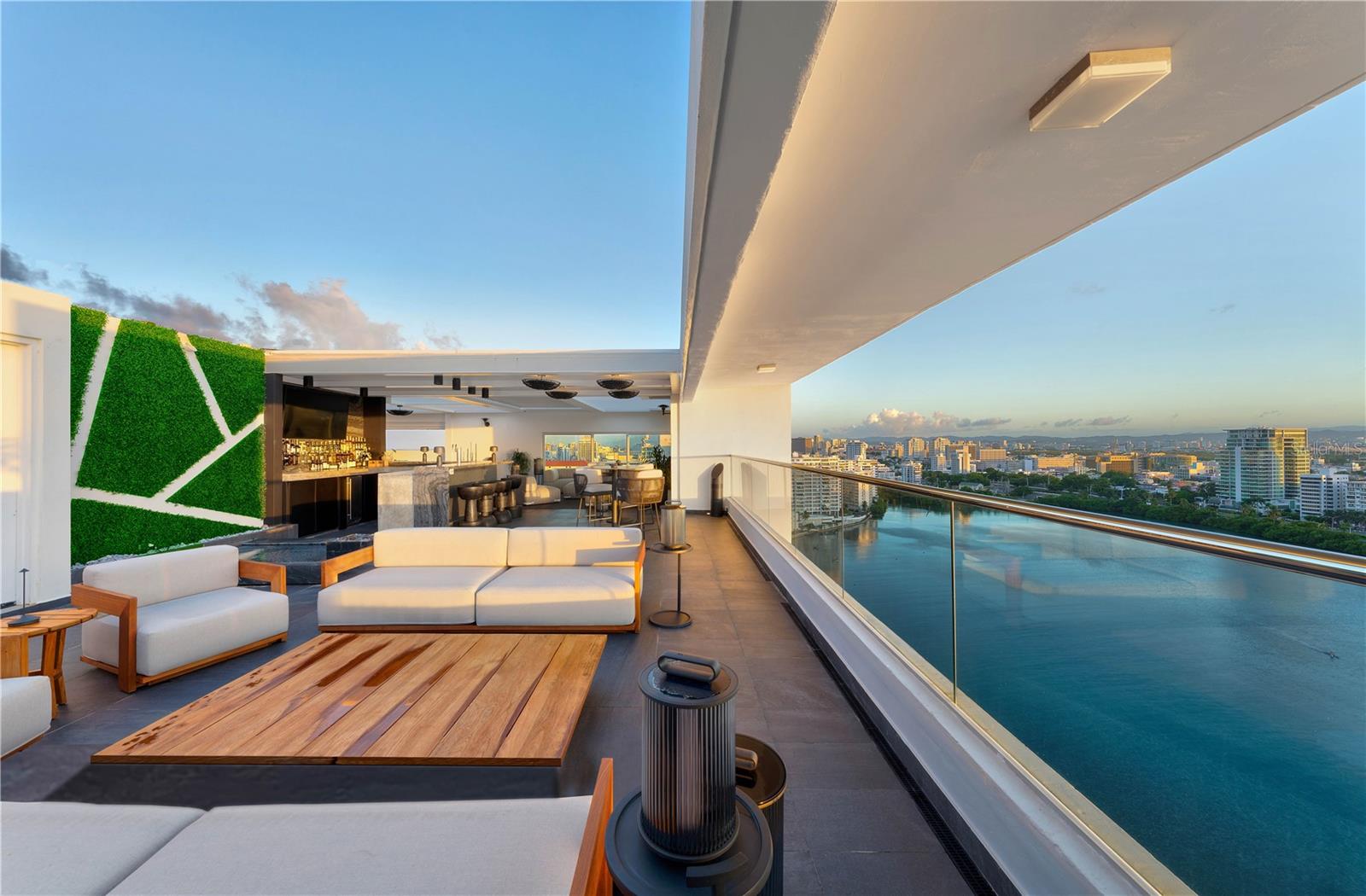 ***SOLD*** No expense spared with this exceptional penthouse, a masterpiece spanning over 3,000 square feet of captivating terraces that command unparalleled views of the ocean, lagoon, mountains, and city. The meticulously designed interiors encompass a sprawling 6,426 square feet, forming a triple mint-condition triplex within a premier full-service condominium. Crafted by the acclaimed interior designer Fernando Rodriguez, the private elevator landing unveils a magnificent sun-drenched gallery adorned with lofted ceilings and a panoramic 360-degree vista. The southern expanse hosts three distinguished den and living spaces, complemented by a Moroccan-inspired oversized triple pendant lighting fixture, a custom-built wine cellar securing 200 bottles, and a gourmet Boffi Italian kitchen featuring a Wolf Induction stove, Miele ovens, and Subzero double refrigerator. All leading seamlessly to an expansive terrace overlooking the lagoon and city. At the northern end, a game room with a full bar and a 100" wall inset 4k TV provides awe-inspiring views of Condado Beach ocean and skyline. The elegant living room, adorned with full house automation, boasts oversized floor-to-ceiling windows framing breathtaking ocean vistas to the East. Connecting to the game room and fully equipped bar with Herringbone blonde wood floors is a state-of-the-art office suite with dramatic ocean views, complete with video conferencing tools, interactive TV, and encryption capabilities. Two half baths complete this level. Private quarters are on the first floor, accessible by direct elevator, feature striking backlit onyx floor-to-ceiling art walls. The primary suite, fully equipped with a lagoon-facing study, hidden ceiling TV, kitchenette, and an expansive closet in ashtone Italian cabinetry, leads to a luxurious bath with onyx, marble, and full cut stone. The floor includes two guest rooms with full baths, a laundry suite, double linen closets, and two back stairs. The third floor, accessed by stairs or private in-apartment elevator, unveils a rooftop terrace with unparalleled views of San Juan south facing, Lagoon and west towards the Old City. An electronic sunlight sky pergola graces the expansive space with a commercial-grade outdoor bar, gourmet summer kitchen, wood-burning pizza oven, and cutting-edge technology. Inside, the hallway leads to a second rooftop featuring an elevated zero-edge pool, a beautifully appointed sunning area, and an outdoor shower. With too many lavish details to note, the apartment is in triple-mint condition and was completed in 2020, including 5 garage parking spaces. 1004 Ashford Avenue is a distinguished full-service condominium, with a fitness center, outdoor inground lagoon facing pool with lounge and private storage.