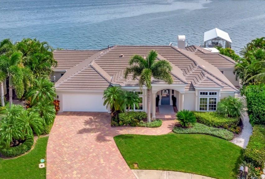 Welcome to a coastal dream come true! This meticulously renovated home features a breathtaking 160 feet of open water views. Nestled in the coastal paradise of Island Estates, this sanctuary boasts 4 bedrooms plus a bonus room, 3 bathrooms, and a spacious 2-car garage. This home has undergone a recent floor plan transformation in 2021, making it ideal for relaxed living and lavish entertaining. Nearly every room in the house provides you with a stunning water view, ensuring that you're always surrounded by natural beauty. The chef's kitchen is a masterpiece, featuring quartz countertops and a large island (seating for 4), Wolf appliances that includes a 6-burner gas cooktop, hood, built- in wall oven, convection microwave, as well as a Sub-Zero 36 inch column refrigerator, Sub-Zero 30 inch column freezer, an XO 24 inch beverage refrigerator, 24 inch dual zone wine cooler (46 bottles), Bosch paneled dishwasher and lighting in and under the cabinetry. Open to the kitchen and dining room, the great room is a striking centerpiece, featuring a gas fireplace with stacked stone, remote solar shades, built-in shelving and a seamless connection to the outdoor haven through a wall of 5 sliding glass doors. Here, you'll discover an updated saltwater pool and spa surrounded by travertine pavers, accentuated by LED lighting and a sleek PebbleTec finish. Savor exceptional waterfront dining beneath the commercial grade cantilever umbrella, where the Lynx gas grill and hood await, and the outdoor bar comes complete with a beverage fridge, an ice maker, ample storage and a trash drawer. Boating enthusiasts will be delighted by the deep water Azek composite dock supplied with water and electric, complete with wrapped pilings, a covered boathouse (with a 25K lb lift) and an additional 6K lb lift. The primary bedroom invites you to live the waterfront dream, with french doors leading to a covered and waterfront patio. The primary suite features a recently renovated bathroom featuring a spacious walk-in shower with marble walls and flooring, custom cabinetry, a soaking tub, Restoration Hardware mirrors, faucets, lighting, hardware and a custom walk-in closet. On the opposite side of the home, two of the three secondary bedrooms enjoy waterfront views, with one boasting an ensuite bathroom featuring a new custom vanity and quartz countertop, a walk in shower, new Restoration Hardware mirror, faucet, lighting, hardware and a new TOTO toilet. The third secondary bedroom is perfectly situated and is adjacent to another secondary bathroom, which showcases a new custom vanity, marble tile in the walk in shower and flooring, and a new TOTO toilet. Additional highlights of this exceptional property include a newer tile roof (2019), new hardwood floors throughout the house, accented by marble and tile bathroom floors. All doors and trim have been upgraded to solid wood, and new fans and lighting fixtures enhance the entire residence. Freshly painted walls, ceiling, and trim add a modern touch, while shiplap accents in the ensuite bathroom and hallway exude coastal charm. You'll also enjoy the benefits of a whole house water softener, newer ductwork (2019), REME Halo air purifiers on both air handlers, double pane windows, tinted windows and sliders, a sea wall cap replacement in 2015, and a tankless water heater. This is waterfront living at its finest, offering not just a home, but a lifestyle. Don't miss the opportunity to make this your own personal paradise.
