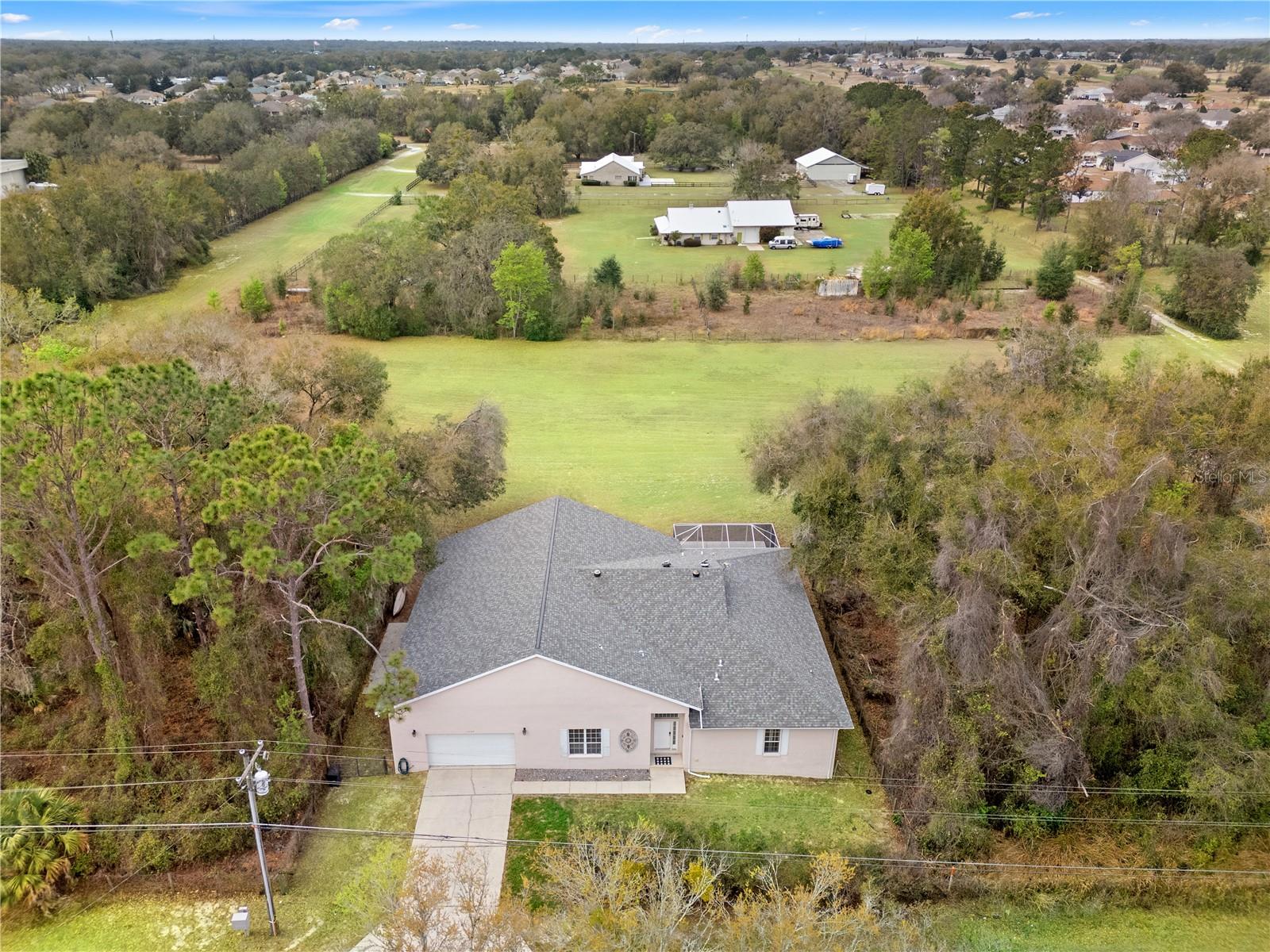 PRICED BELOW APPRAISED VALUE! Experience true fly-in living with this exceptional airpark estate positioned directly on a 3,500 foot private grass runway. Ideally located near The Villages and Ocala, the property offers convenient access to shopping, dining, medical, and equestrian amenities while maintaining the charm and privacy of Old Florida surroundings. Lake Weir sits just across the street, offering lakefront dining, world class bass fishing, boating, and waterfront recreation. Mountain bike and Outdoor enthusiasts will appreciate proximity to the Marjorie Harris Carr Cross Florida Greenway and the Santos Trails, both known for exceptional mountain biking and hiking experiences throughout Central Florida. The renowned WORLD EQUESTRIAN CENTER in Ocala is also within easy reach, adding premier equestrian events, fine dining, and year-round entertainment to the lifestyle appeal of this exceptional location. The property itself features an attached approximately 3,000 square foot aircraft hangar, delivering a rare combination of residential comfort and aviation functionality. For buyers seeking a Florida airpark home with direct runway access, this property represents one of the most compelling values currently available. Designed with a desirable split floor plan, the home includes two oversized primary suites, each with generous walk-in closets and en suite baths, ideal for multi-generational living, extended guests, or dual primary accommodations. Upstairs features a large third bedroom that can also function as a secondary living area, media room, or private guest retreat. Tile flooring spans the entire main level for durability and low maintenance, while the open concept living, dining, and kitchen areas create seamless flow for entertaining. The kitchen is thoughtfully appointed with abundant counter space, bar seating, and a large walk-in pantry, making it equally suited for everyday living or hosting after a day in the sky. The attached hangar is equipped with a full bathroom and separate wash sink, offering substantial space for aircraft storage, maintenance, workshop use, or luxury vehicle storage. Direct access to the private grass runway eliminates the need for off-site hangar rentals and delivers the ultimate convenience for aviation enthusiasts. If you have been searching for a fly-in community home near Ocala, a private runway property in Central Florida, or a residence with an integrated aircraft hangar, this opportunity checks every box. Properties that combine this level of aviation infrastructure, functional layout, and strategic location rarely come to market. Schedule your private showing and experience runway-front living at its finest.