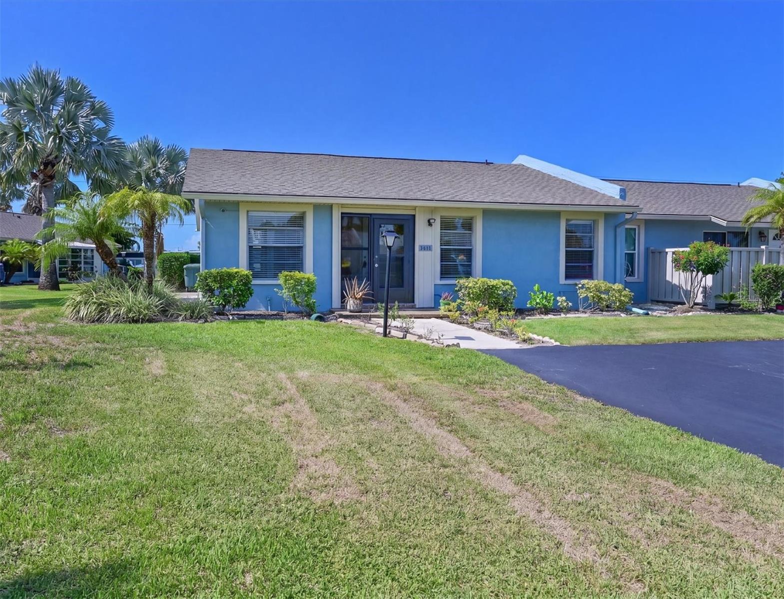 Welcome to Cortez Villas, a sought-after 55+ community offering a clubhouse, heated pool, and an unbeatable West Bradenton location. This beautifully maintained, move-in ready END UNIT villa features vaulted ceilings, natural light, and is being sold TURNKEY FURNISHED. Park right at your front door with an oversized driveway that accommodates multiple vehicles. Recent updates include a NEW ROOF (2024), NEW DRIVEWAY PAVING (2025), NEW EXTERIOR PAINT (2026), and attractive laminate flooring throughout the home. The remodeled kitchen is designed for both style and function with shaker cabinetry, granite countertops, wine rack, and additional cabinetry. The wall separating the kitchen and living area has been opened to create a bright, open-concept floor plan with a breakfast bar. Enjoy peaceful backyard views with no rear neighbors directly behind you. The glass-enclosed lanai opens to a spacious side patio--perfect for grilling, entertaining, or relaxing around a fire pit. An attached storage room provides added convenience. The spacious primary suite offers vaulted ceilings and an en-suite bath with walk-in shower. The versatile DEN includes an area for closet space and can easily serve as a home office, hobby room, or be converted into a third bedroom if desired. Ideally located directly across from a public golf course and just minutes to Publix, shopping, dining, banking, the YMCA, GT Bray Park with tennis, pickleball, fitness facilities. Close to Gulf beaches. If you are looking for a low-maintenance Florida lifestyle in a prime location, this updated villa is a must see!