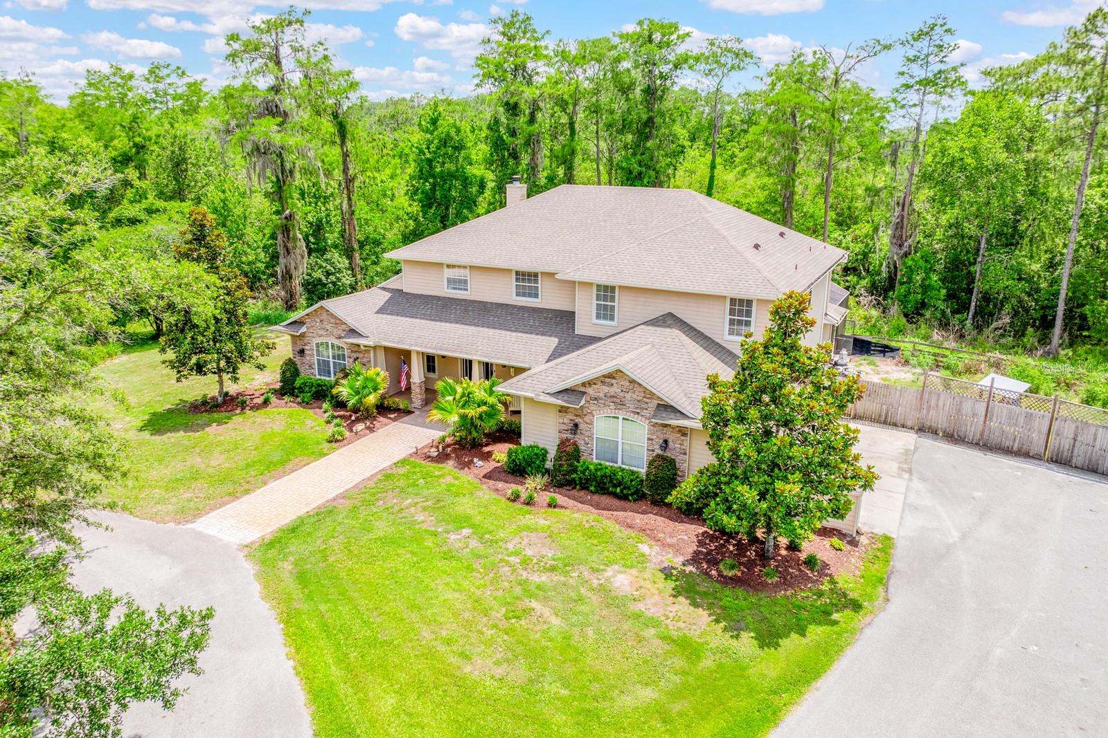 Welcome to your personal paradise of 5 ACRES ~ PRIVATE ~ WOODED in the GATED COMMUNITY of Lake Pickett Woods! This beautifully UPDATED ~ POOL HOME delivers the space, privacy and lifestyle you have been searching for in Chuluota/Oviedo. Recent improvements include FRESH INTERIOR & EXTERIOR PAINT, a NEW UPSTAIRS A/C UNIT (2024) and WATER SOFTENER (2024), NEWER ROOF (2021), septic service completed two years ago, and double pane windows for added energy efficiency. Thoughtfully designed with elevated finishes and room for everyone to spread out, this 5-bedroom, 4-bath home also features a dedicated OFFICE and an ENCLOSED BONUS/LOFT that can easily function as a sixth bedroom, media/movie room or flex space to fit your needs. The interior delivers soaring ceilings, abundant natural light and seamless living spaces that create an inviting atmosphere from the moment you walk through the front door. The spacious living room is anchored by a stacked stone WOOD BURNING FIREPLACE and a dramatic WALL OF SLIDING GLASS DOORS that open to your private LANAI & SCREENED POOL/SPA for effortless INDOOR/OUTDOOR Florida living. The timeless kitchen truly serves as the heart of the home with rich solid wood cabinetry, tiled backsplash, UPGRADED STAINLESS STEEL APPLIANCES including a built-in DOUBLE OVEN, oversized ISLAND with bar seating, pendant and recessed lighting, and easy flow into both the casual dining area and versatile formal dining space with French door access to the paver deck and pool area. TILE & LUXURY VINYL PLANK flooring run throughout the main living spaces, office and primary suite, while guest bedrooms feature comfortable carpeting. The OVERSIZED MAIN FLOOR PRIMARY SUITE suite offers a peaceful retreat complete with direct lanai and pool access, a huge WALK-IN CLOSET, ELECTRIC FIREPLACE for added ambiance and a well-appointed en-suite bath. Upstairs, two of the three secondary bedrooms enjoy en-suite bath access, and an additional main floor bedroom creates ideal accommodations for guests or multi-generational living. With multiple gathering spaces and flexible room configurations, this home was thoughtfully designed for both everyday comfort and entertaining on any scale. Beyond the home itself, Lake Pickett Woods is known for its serene setting, five acre homesites and PRIVATE LAKE ACCESS nearby, giving residents the opportunity to enjoy boating, fishing and the true Central Florida lake lifestyle surrounded by nature. Tucked away amongst the trees yet conveniently located with easy access to TOP-RATED SCHOOLS, Oviedo, Waterford Lakes, shopping, dining and major roadways – this is a rare opportunity to enjoy peaceful acreage living without sacrificing convenience. Live the lake life the way you have always wanted in Lake Pickett Woods. Call today to schedule your tour and fall in love with your new HOME SWEET HOME!