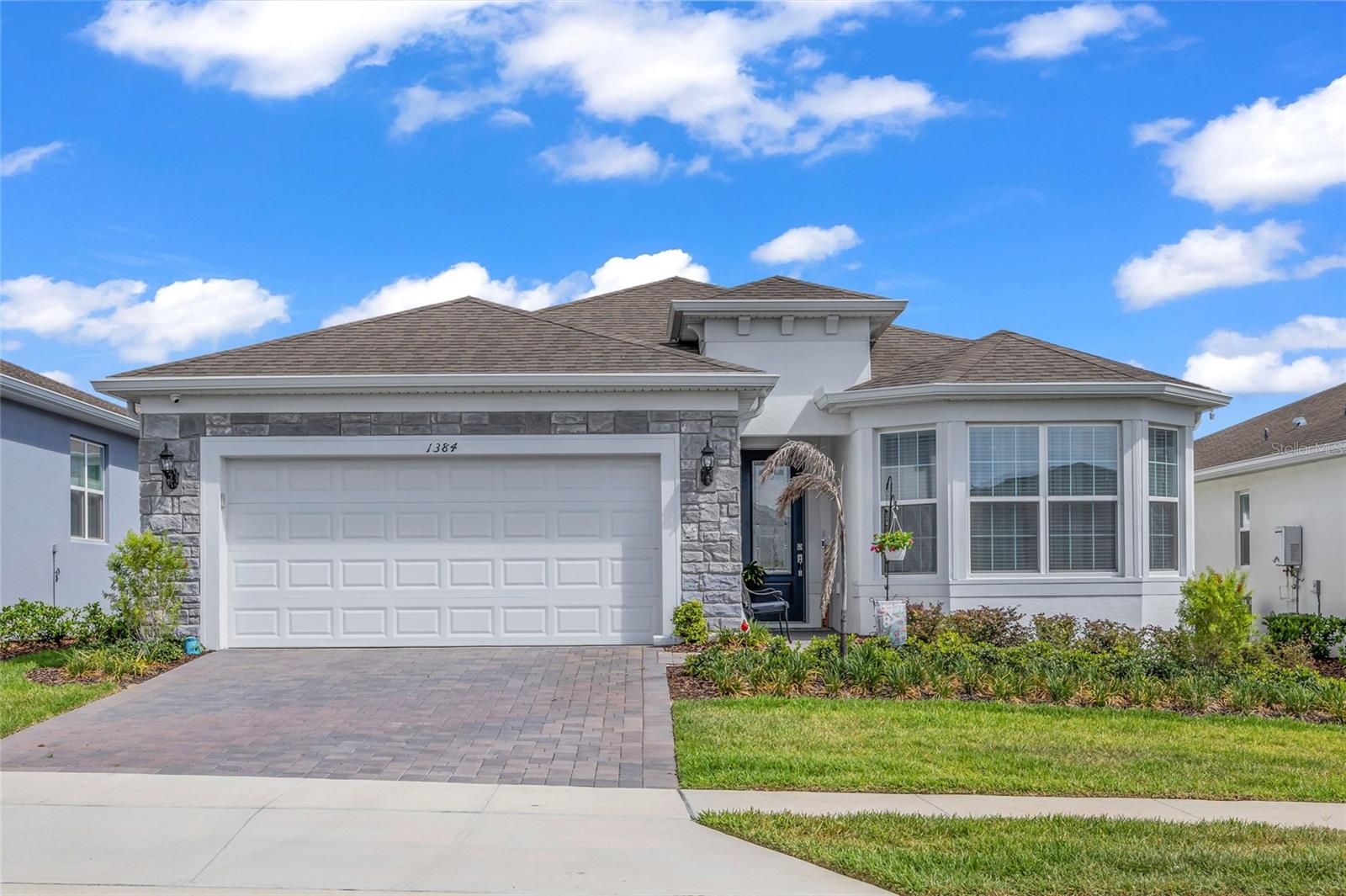 Welcome to this nearly new 3-bedroom, 2-bath residence in the highly sought-after 55+ community of Del Webb Minneola, where thoughtful upgrades, flexible living spaces, and low-maintenance, resort-style living come together seamlessly. Built in 2025, this home presents like a model, enhanced with stone exterior accents, a glass inset front door, and elevated finishes throughout.
Inside, you’ll find an open-concept layout anchored by a bright, modern kitchen featuring a gas range, stainless steel appliances, abundant cabinetry, and an oversized island that flows effortlessly into the main living and dining areas, deal for both everyday living and entertaining. The home is further elevated by 8-foot doors throughout, upgraded lighting in the living and dining spaces, and ceiling fans with integrated lighting in nearly every room.
A standout feature is the expanded front flex room, bumped out from the original floor plan to capture additional square footage and natural light, making it perfect for a home office, sitting area, or formal living space. Just beyond the main living area, a sunroom extension provides a bright, enclosed retreat for relaxing or hobbies, while the screened lanai offers a comfortable outdoor space to enjoy Florida living year-round.The spacious primary suite is designed for comfort and accessibility, featuring a zero-entry walk-in shower, dual vanities, and a generously sized walk-in closet. The upgraded laundry room includes a utility sink, base cabinetry, and upper cabinets for added functionality.
The garage has been thoughtfully enhanced with an extended layout, finished epoxy flooring, a dedicated workspace cove, and attic access with built-in stairs, providing exceptional storage and versatility without compromising parking.
Additional features include gutters and downspouts, adding both function and peace of mind. With premium upgrades throughout and access to Del Webb’s planned resort-style amenities, this home offers the best of new construction living, without the wait.