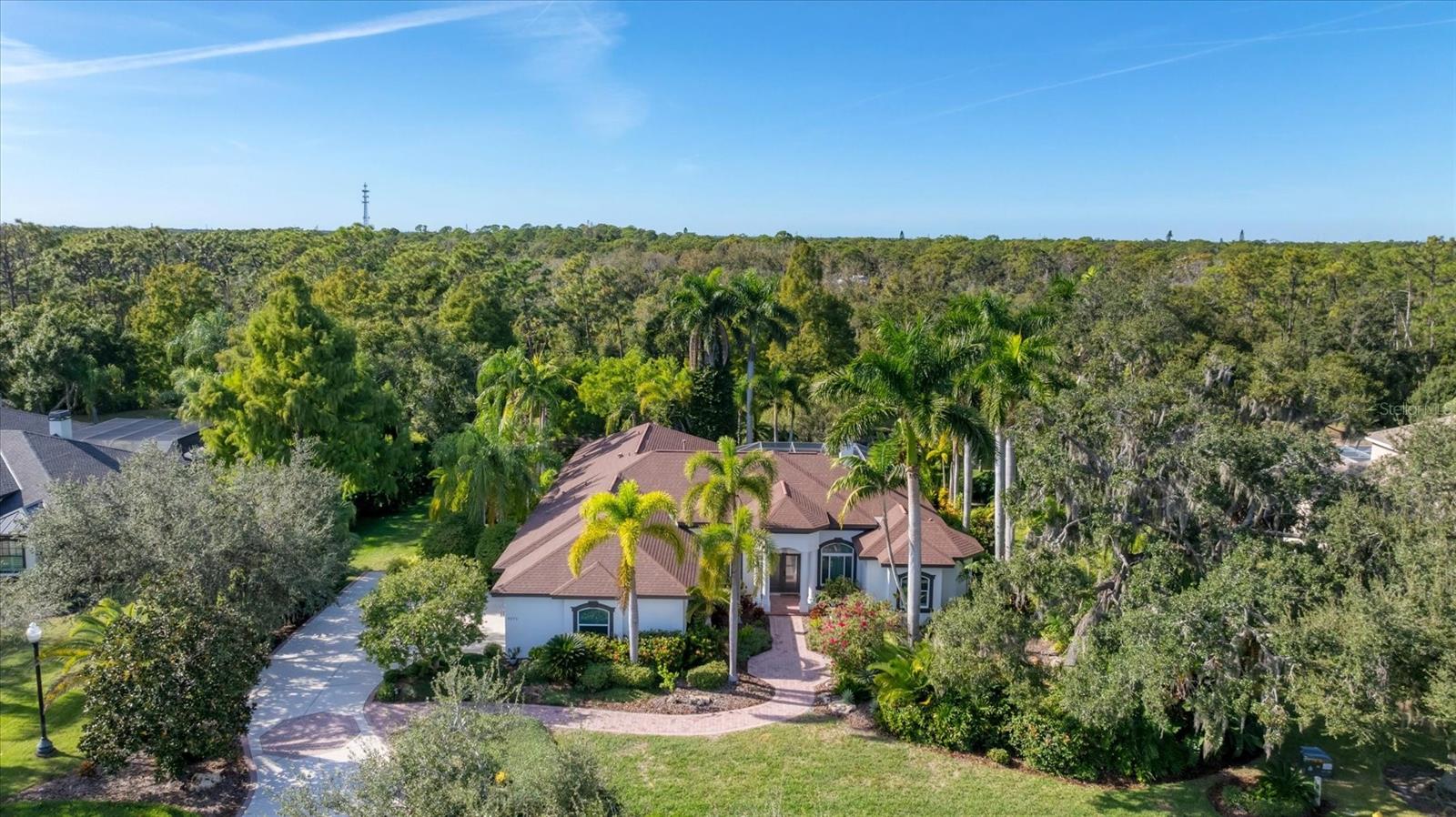Stunning River Club Estate is set on almost three acres and backing to the tranquil Braden River, offering sweeping views of water, mature woods and abundant wildlife. Thoughtfully redesigned for modern living, this residence blends refined interior upgrades with exceptional outdoor spaces. At heart of the home is the completely remodeled kitchen, showcasing an impressive 5-by-10-foot center island, premium cabinetry, quartz and granite countertops, high-end appliances and open connection to the family room. Hurricane impact windows and disappearing sliders create seamless indoor–outdoor living and fill the home with natural light. Designed for year-round enjoyment, the home features two under-roof outdoor living areas, one with a full outdoor kitchen and dining space, and a second covered outdoor living room ideal for relaxing or entertaining. The screened lanai overlooks the gas-heated pool and spa, with peaceful views of the surrounding landscape. Inside, the split-open floor plan offers three bedrooms, each with its own private wing, along with a den/bonus room, formal living and dining areas, and a spacious family room, all finished with travertine flooring. The living room is enhanced by a gas fireplace with custom detailing. The primary suite offers direct access to the outdoor living area, two walk-in closets, and a luxurious bath with a walk-around double shower and separate soaking tub. Additional highlights include a recently painted exterior and an oversized three-car side-load garage with 93” inch high garage door to fit your large truck or suv and paver flooring, a rare and attractive feature in a garage. A new roof (2018) and new air conditioner (2019) provide added peace of mind. The home itself is in X flood zone, while portions of the expansive acreage extend into the AE zone, offering protection and scenic beauty. In desired River Club, a golfing community known for low HOA fees and no CDDs, this exceptional property is just minutes from Lakewood Ranch’s shopping, dining, UTC Mall, the new Mote Marine Laboratory, top-rated schools, downtown Sarasota and Gulf beaches. A rare combination of luxury updates, privacy and breathtaking natural surroundings, this estate represents an extraordinary opportunity in one of the area’s desirable communities.