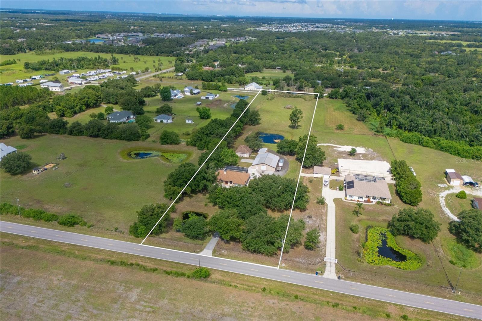 Rare opportunity to own a private 5+ acre estate in Parrish with endless possibilities! This unique property features a spacious 4-bedroom, 3-bath main residence with a 2-car garage, offering comfortable living and plenty of room to spread out. Inside, you'll find a wood-burning fireplace that beautifully separates the family room from the study/den, creating warmth and character throughout the home. Enjoy Florida living at its finest with a large screened lanai overlooking the private pool and peaceful acreage. The property also includes a separate 2-bedroom, 2-bath guest home with approximately 900 square feet of living space plus a 400-square-foot enclosed, air-conditioned lanai—ideal for multi-generational living, guests, a home office, or rental potential. Bring your hobbies, business, and recreational vehicles! Additional improvements include a detached 30x15 garage and an impressive 3,000-square-foot workshop offering exceptional space for equipment, storage, projects, or a home-based business. Two picturesque ponds enhance the beauty of the property, while a private shooting range at the rear of the acreage provides added recreational enjoyment. With ample room for boats, RVs, trailers, and all your outdoor toys, this one-of-a-kind property combines privacy, functionality, and country living without sacrificing convenience.
