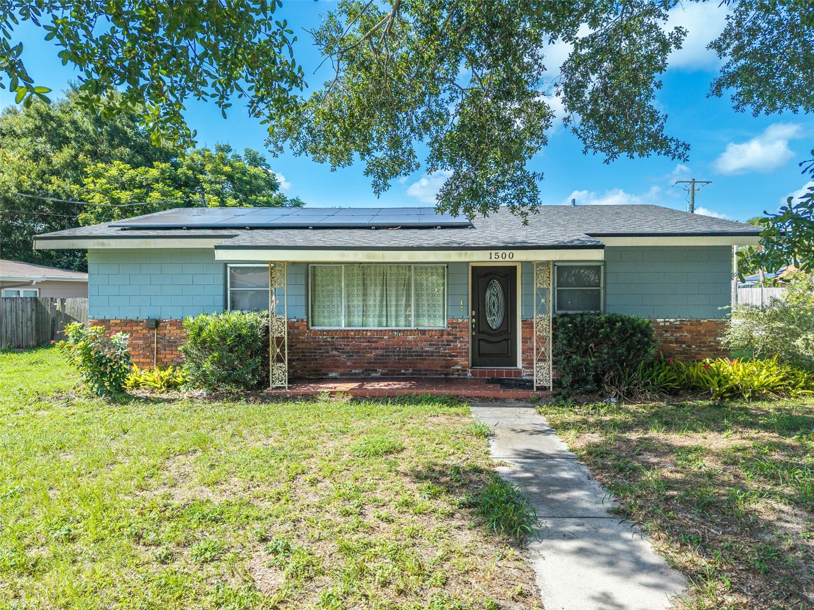 Welcome to this spacious 4-bedroom, 2-bathroom home offering a wonderful blend of timeless character, flexible living space, and outstanding outdoor potential. From its classic brick exterior with charming blue accents to the energy-efficient rooftop solar panels, this property is designed for both comfort and value. Inside, you'll find a bright and inviting living area with durable tile flooring and a decorative leaded-glass front door that creates a warm first impression. The spacious eat-in kitchen features crisp white cabinetry, generous counter space with dark countertops, and plenty of room for everyday meals and gatherings. A versatile BONUS FLEX ROOM showcases rich pine wood paneling, built-in shelving, and direct access to the backyard, making it ideal as a family room, media room, game room, home office, or hobby space. The primary bedroom, flex room, and second bedroom feature comfortable carpeting. The four well-sized bedrooms provide flexibility for families, guests, or remote work needs, while the functional layout offers comfortable everyday living. Step outside to discover a large, FULLY FENCED BACKYARD with endless opportunities to create your own private retreat. The expansive concrete patio with brick accents provides the perfect setting for outdoor dining, entertaining, weekend barbecues, or simply relaxing under the Florida sunshine, with plenty of additional yard space for a garden, play area, or future outdoor enhancements. Major updates include a 2015 water heater and a 2012 HVAC system, plus the added value of a SECOND BACK UP HVAC UNIT that is not hooked up to the house. Ideally located in the heart of Winter Haven, this home places you just minutes from Downtown Winter Haven, the renowned Chain of Lakes, Chain of Lakes Park, Polk State College, and LEGOLAND® Florida Resort. A NEWLY BUILT SCHOOL IS LOCATED just a few blocks away, while the recently renovated walking, biking, and running trail surrounding beautiful Lake Elbert offers an excellent opportunity to enjoy an active outdoor lifestyle. Everyday conveniences are within easy reach, including Publix, Walmart, Lowe's, shopping, dining, and medical facilities. Winter Haven Hospital is just 7 minutes away, Santiago's Market is approximately 10 minutes away, while Winter Haven Regional Airport and Auburndale Speedway are both just a 17-minute drive. With quick access to US-17, US-27, and the Polk Parkway, commuting to Lakeland, Orlando, and Tampa is simple. Blending vintage charm with modern comforts and an unbeatable location close to the area's top amenities, recreational opportunities, and everyday conveniences, this property is the perfect place to call home.
