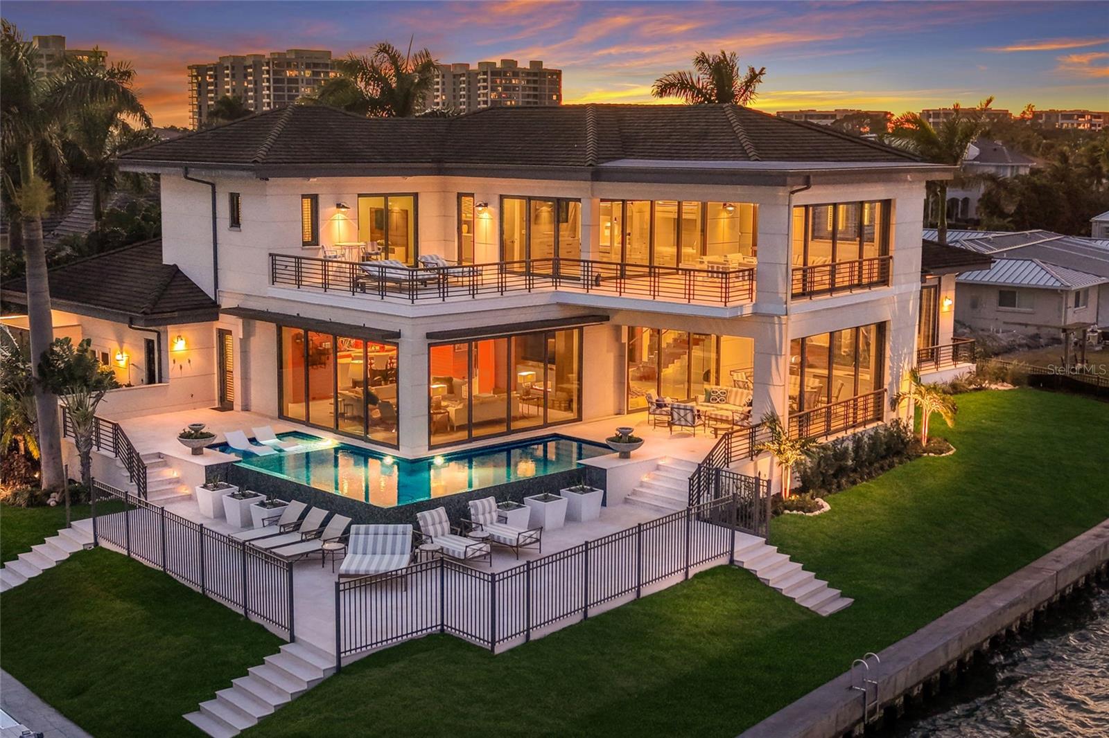 Longboat Key's iconic, award winning, "Summer House" by Architect John Potvin, Builder Murray Homes and Landscape Architect Michael A. Gilkey. Perched on 260 feet of waterfront, one of the most coveted point lots in Country Club Shores with Deeded Beach Access, this coastal contemporary offers views across Sarasota Bay, the city skyline, and the Ringling Bridge. 2016 Home and Seawall. Designer-furnished and move-in ready, the pinnacle of waterfront luxury. Built with resilience and sophistication, the home and garage are elevated above flood impact levels and experienced no water intrusion throughout recent storm events. The property also benefits from a second, engineered seawall that strengthens the foundation and supports the outdoor terraces, offering both structural security and enduring coastal comfort.  Enjoy a 63’ Trex dock with a 14,000-lb lift, 3,000-lb kayak/paddleboard elevator, water and electric, and outdoor shower. A 260' vinyl seawall and breakwater, completed in 2016, ensures peace of mind and lasting stability.  Inside, 4,553 sq. ft. of refined living space showcases craftsmanship and advanced technology, including a full-home Lutron system, Windoor 8100 sliders, Doors In Motion wall systems, and a comprehensive security network. Luxurious limestone flooring on the main level, engineered white oak flooring upstairs, cypress outdoor ceilings & soffits, Level 5 drywall, and warm walnut beams. The main living area impresses with soaring 11’4” ceilings and a dramatic two-way natural gas fireplace. The dining room continues the understated luxury with walnut detailing, automated shades, and its own fireplace. The chef’s kitchen is a culinary showpiece, featuring Cristello quartz countertops, walnut veneer cabinetry, Miele appliances, induction cooktop, warming drawer, Grohe filtration, veggie sink with disposal, and a smart dumbwaiter connecting to the second floor.  Outdoor living is unparalleled. A 350-sq-ft covered terrace boasts Turkish, Alexander Cream limestone flooring, Wolf grill, marble countertops, refrigeration, big-screen TV, and retractable openings for seamless indoor-outdoor entertaining. An Infiniti edge saltwater pool with tanning shelf and gas fire bowls create a breathtaking setting.
The first-floor owner’s suite with a private balcony, custom walnut headboard with pop-up TV, and a spa-inspired bath featuring floor-to-ceiling marble, dual sinks, heated floors and towel racks, double shower, and a walnut walk-in closet with built-in safe. Upstairs, a striking glass-and-walnut floating staircase leads to 10’ ceilings, a versatile 4th bedroom with built-in bunk beds, wet bar, refrigeration, dumbwaiter access, and two fully opening walls to covered and open-air terraces.  Pocketing glass doors, Pecky cypress ceilings, Infratech heaters, sweeping skyline views sun terrace for relaxing or entertaining. Every room has an open Bay view. terrace access. Additional luxury features include a dedicated laundry room, powder room, 2-car garage with golf cart charging, epoxy flooring, built-ins, and a natural-gas generator supporting 400-amp service. This is a rare convergence of architectural brilliance delivering Sarasota living at its most elevated and effortless.