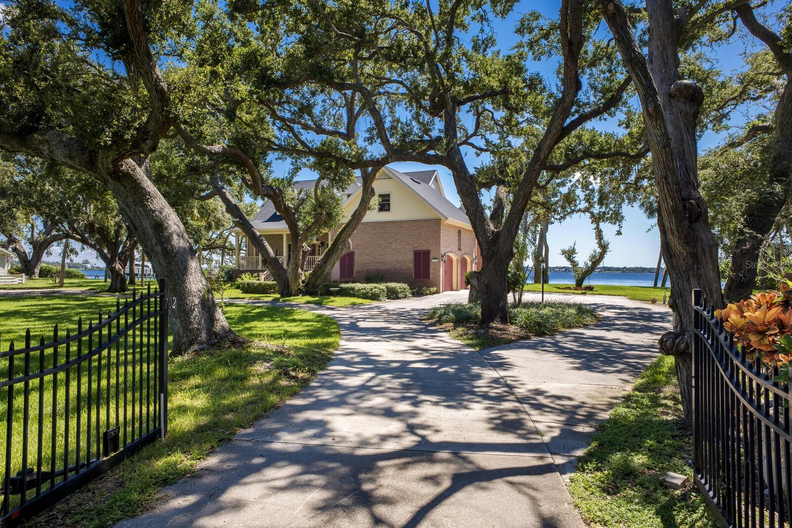STUNNING RIVERFRONT CUSTOM ESTATE ON 1.42 ACRES WITH 223 FEET OF DIRECT MANATEE RIVER FRONTAGE!!! Tucked behind a private gated entry, a winding drive meanders beneath a canopy of majestic, centuries-old oak trees, setting the stage for a home that exudes timeless elegance and refined Southern charm. This elevated brick estate, masterfully designed and impeccably maintained by its original owners, blends classic architectural sophistication with the serene beauty of its natural riverfront surroundings. Spanning over 4,200 square feet of inspired living space, this residence offers 3 bedrooms plus a dedicated office and 3.5 baths, all crafted with meticulous attention to detail, volume ceilings, & an abundance of natural light. The grand foyer makes a striking first impression with its tall ceilings, custom stained-glass accents, and sweeping staircase. Just beyond, an office provides a perfect space for working from home. The heart of the home is the expansive great room, where panoramic water views steal the spotlight. A stately fireplace framed by built-ins, 10-foot ceilings, and multiple gathering areas create a welcoming space for both intimate evenings and large-scale entertaining. The gourmet chef’s kitchen is as functional as it is beautiful, boasting white custom cabinetry, granite countertops, premium stainless-steel appliances, and an oversized center island with additional storage. Adjacent is a butler’s pantry, fully outfitted with additional cabinetry, prep sink, second dishwasher, refrigerator, and storage. An airy, light-filled dining room framed by oversized windows overlooks the river, providing a gorgeous backdrop. For year-round enjoyment, the enclosed Florida room offers walls of glass that bathe the space in natural light and water views. The luxurious main level primary suite is a true retreat, featuring a large bay window, dual walk-in closets, and a private sitting area. The spa inspired ensuite bath offers his & her vanities, a Jacuzzi tub, and a walk in shower. Upstairs, two generously sized guest suites each include walk in closets & private ensuite baths, while a spacious bonus area provides a comfortable lounge or playroom. Above the garage, a sprawling flex room awaits transformation into a hobby room, media retreat, or ultimate “man cave.” This estate also offers abundant parking and storage with a 2-car attached garage and a separate 3+ car detached garage, perfectly suited for car collectors or hobbyists. Outdoors, the riverfront grounds are nothing short of magical. Beneath the shade of towering oaks, relax in Adirondack chairs and take in the mesmerizing sunsets. With deep water access and no bridges, this property is a boater’s dream with easy access to Tampa Bay & the Gulf. There is also ample space for a resort-style pool to further elevate the lifestyle experience. Situated just minutes from the Bradenton Yacht Club and the natural splendor of Emerson Point Preserve’s 365 acres of trails and kayak launches, this home offers an unparalleled balance of privacy, recreation, and convenience. The world-famous beaches of Anna Maria Island are just a short drive away and quick access to I-75 for effortless travel. With no HOA or deed restrictions, your waterfront lifestyle can be as relaxed—or as indulgent—as you desire. This extraordinary estate represents the pinnacle of riverfront living—an irreplaceable retreat of timeless beauty, elegance, and unparalleled access to Florida’s most coveted waters.