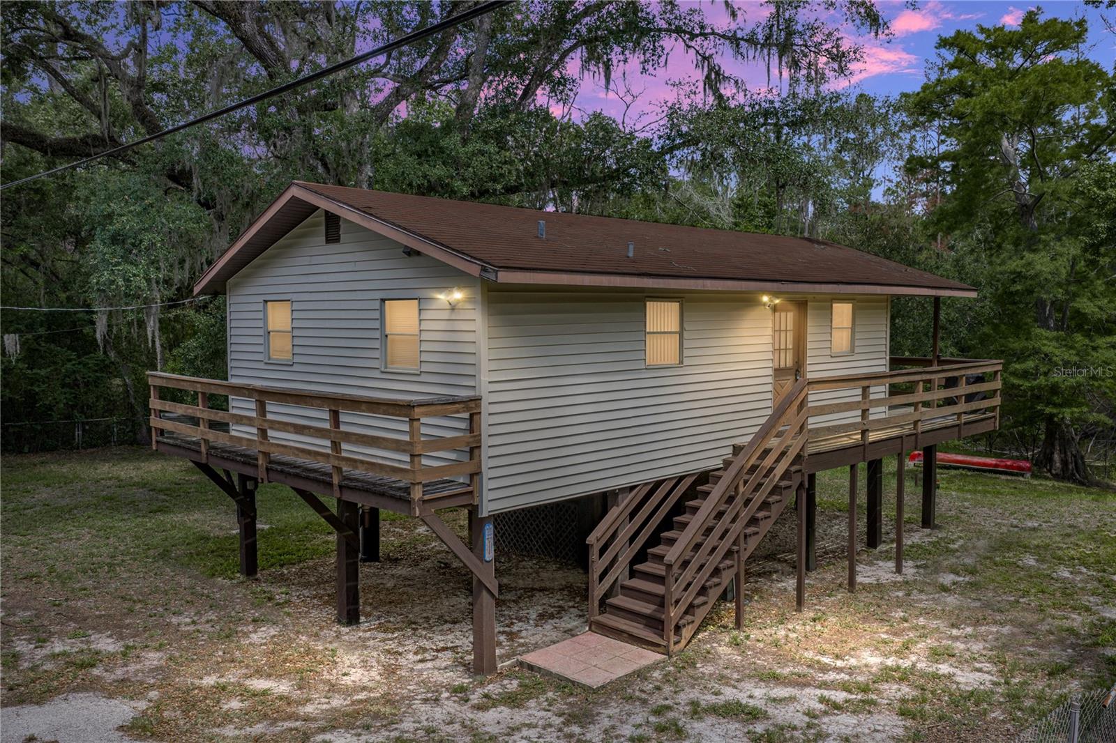 Your Riverfront Paradise Awaits! With 111 ft of Withlacoochee River frontage and a stilt-home design ready for waterfront living, this 2 bedroom, 1 bath home offers the kind of setting buyers dream about and vacation guests search for! Set on a gorgeous 1/3 acre with covered deck views over the water, the property is well suited for a personal river retreat, weekend getaway, or rental opportunity for those drawn to fishing, canoeing, and quiet Florida scenery. Inside, laminate flooring flows through most of the home, and ceiling fans in each room help keep the breeze moving from space to space. In the living room, two sets of sliding glass doors frame the backyard and river beyond, drawing the water view right into the main living area. The L-shaped layout gives you flexibility for two seating areas, a dining setup, or a cozy river-view lounge that opens directly to the covered deck. The kitchen is equipped with a 4 piece appliance package, breakfast bar seating, and ample cabinet and pantry storage, keeping the space practical for full-time living, weekend stays, or guests. Both bedrooms sit near the home’s full bathroom, complete with a tub/shower combination. Downstairs, the stilt-home design adds excellent function with covered parking beneath the home, plus plenty of room to park in the expansive yard. A gated entry, chain link fencing, and a beautiful balance of trees and open space add to the property’s usability while keeping the riverfront setting easy to enjoy. Head toward the back of the property and the lifestyle truly comes into focus. Launch the canoe, cast a line, set up a chair near the water and simply enjoy the beauty of your own stretch along the Withlacoochee River. Whether you are searching for a full-time home on the water, a personal escape, or a vacation rental opportunity, this property offers room for possibility in a setting that is hard to recreate. Just minutes from I-75, you can enjoy peaceful waterfront living while staying within easy reach of Tampa Bay hotspots. Call today to schedule your private showing!