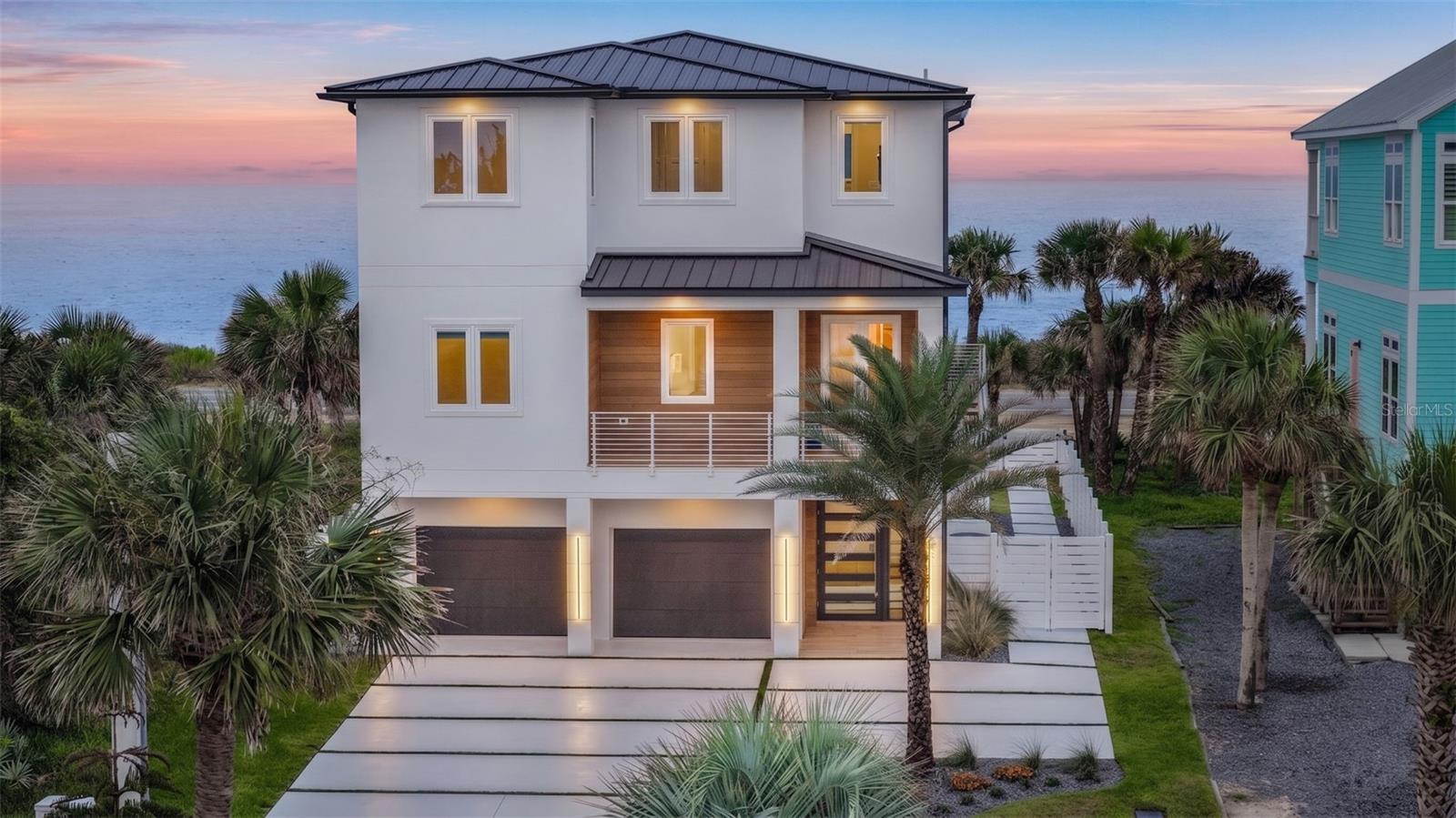 Virtually Staged. A shoreline masterpiece unlike anything else in Flagler Beach, 2214 N Central Ave is a one-of-a-kind modern oceanfront estate where refined architecture, exceptional construction, and an extraordinary coastal lifestyle converge. Completed in Nov. 2024, this legacy residence was designed with no expense spared, offering contemporary elegance and uncompromising quality in one of Northeast Florida's most coveted waterfront settings. Positioned between the Atlantic Ocean and the Intracoastal Waterway on iconic A1A, the home captures rare dual-water views. Wake to spectacular Atlantic sunrises and unwind with peaceful Intracoastal sunsets as dolphins and migrating whales provide an unforgettable backdrop from your private terraces. Built as a true coastal fortress, the residence is constructed entirely of reinforced concrete across all three levels with approximately 24 concrete pilings extending 25 feet deep. Features include impact windows and doors, impact-rated garage doors, a standing seam aluminum roof, a new seawall, underground drainage, foam insulation, and elevated construction in Flood Zone X, delivering exceptional strength, efficiency, comfort, and peace of mind. Spanning approximately 3,800 square feet, the open-concept design showcases a dramatic 24-foot wall of sliding glass framing panoramic ocean views. The chef's kitchen is anchored by a stunning 12-foot quartzite island, custom cabinetry, Thermador Professional Series appliances, gas cooking, and refined designer finishes. Smart lighting, Sono's audio, and a remote-controlled linear fireplace create an atmosphere that is both refined and effortlessly relaxed. The upper level is dedicated to a luxurious oceanfront owner's retreat with a private balcony, dual custom walk-in closets, motorized shades, and a spa-inspired bath featuring a soaking tub, oversized double shower, bidet, and elegant wet-room design. Two additional bedrooms, a full bath, laundry room with beverage refrigerator, and a dedicated oceanfront office with a custom mahogany desk complete the level. Adding exceptional versatility is a fully independent guest residence at 2216 N Central Ave with its own address, private entrance, garage, kitchen, living area, laundry, bedroom, walk-in closet, covered deck, mailbox, and separate mechanical systems, making it ideal for multigenerational living, extended family, executive quarters, or long-term guests. Technology is seamlessly integrated with Samsung SmartThings automation, commercial-grade Wi-Fi, Cat6 wiring, Sono's audio, smart lighting, smart thermostats, smart locks, Moen Flo leak detection, exterior cameras, Ring doorbells, fiber optic capability, and remote management of major systems. Outdoor living is equally impressive with expansive oceanfront terraces, porcelain-tile decking, engineered wood ceilings, an outdoor shower, luxury spa, and thoughtfully designed entertaining spaces. Additional highlights include EV charging stations in both garages, epoxy-finished garage floors, golf cart parking, custom cabinetry, and a tandem three-car garage. Conveniently located approximately 35 minutes from St. Augustine, one hour from Jacksonville, and 90 minutes from Orlando, this exceptional property offers the perfect balance of privacy and accessibility. Whether as a full-time residence, luxury coastal retreat, or multigenerational estate, 2214 N Central Ave presents a rare opportunity to own one of Florida's most distinctive modern oceanfront homes.