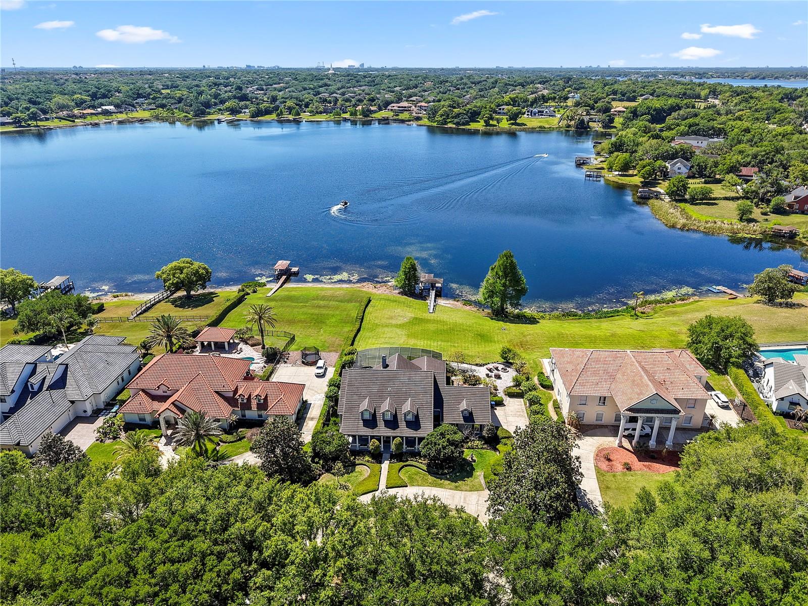 Set within the private gates of Weatherstone on Lake Olivia, this stunning spring fed lakefront residence offers a rare opportunity to enjoy refined living along the peaceful shoreline of Lake Olivia in Windermere. Situated on an expansive lakefront homesite, an increasingly rare find in this area, the property provides exceptional space, privacy, and unobstructed water views. Boasting 6 bedrooms and 4 full baths, the home blends classic design with thoughtful updates and an inviting, functional layout. A charming wraparound front porch creates a warm first impression, surrounded by mature landscaping and tranquil views, perfect for relaxing mornings or unwinding at the end of the day. Inside, natural light fills the home, highlighting soaring ceilings, rich wood flooring, plantation shutters, crown molding, and carefully curated designer details. The open concept design allows for effortless flow between the main living spaces, many of which capture picturesque lake views. At the center of the home, the updated kitchen serves as a true gathering place, featuring generous prep space, a large island, stainless steel appliances, and a spacious dining area. Two oversized walk in pantries, one with a concealed bar, offer both convenience and a touch of character. The primary suite is located on the first floor, offering serene lake views, a spacious custom closet, and a beautifully redesigned bathroom with dual quartz vanities, a soaking tub, and a walk in shower. The first floor also includes a private office with custom built ins, an additional family room, or optional formal dining space, and a full bath. Upstairs, a well planned layout provides flexibility and privacy with five secondary bedrooms, some connected by updated Jack and Jill baths, plus a dedicated workspace with built in features on the landing area. An additional oversized bonus room with closet can easily function as a media room or play space. The home previously had a large loft area which could quite easily be converted back. Additional highlights include a first floor laundry room, abundant storage throughout, an updated tile roof, refreshed exterior paint, and a three car garage with epoxy flooring and built in storage.

Designed for entertaining, the outdoor living space features a covered lanai, summer kitchen, resort style pool, fire pit, artificial turf dog run, and a Trex dock with boat lift, all overlooking the calm waters of Lake Olivia, where you can water ski, have fun on your boat or jet ski’s or just enjoy a calm ride on your paddle boards, the fun is endless. The gently sloping homesite enhances the home’s elevated position, maximizing lake views while naturally directing rainwater away from the property, an often overlooked advantage in Florida lakefront living. It also adds character to the outdoor space, creating a more dynamic and enjoyable setting for both relaxation and play.

With only 13 homes, Weatherstone Ct offers a boutique gated setting just moments from local favorites like The Yellow Dog Eats, parks, top rated schools, and the heart of Windermere. This is lakefront living at its finest, private, spacious, and beautifully appointed. Ideally located with direct access to all the major highways, the home provides seamless connectivity to destinations throughout Central Florida and beyond, while still maintaining a quiet, tucked-away feel.