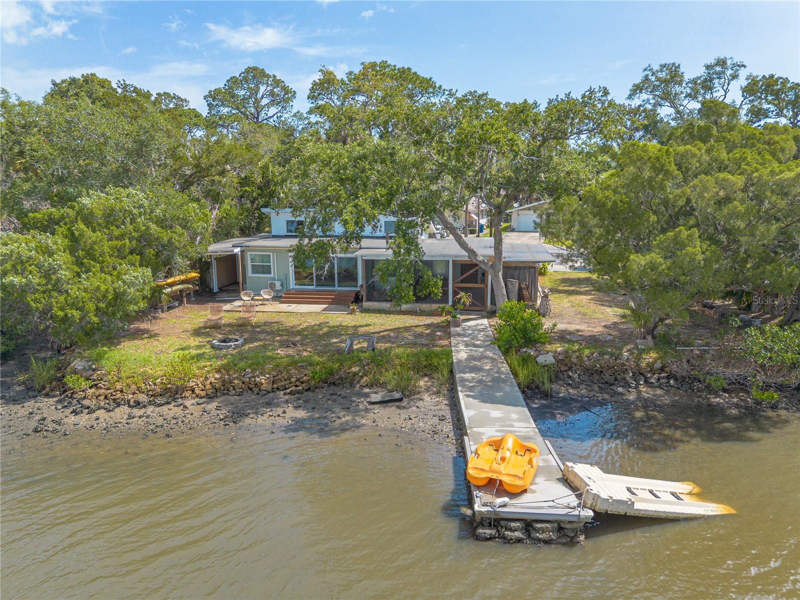 This coastal cottage in Port Orange’s Harbor Oaks/Bay Shore neighborhood is on an oversized waterfront lot with sweeping Rose Bay views. Because the Doris Leeper Spruce Creek Preserve is directly across the water, that view is yours forever. Inside, vaulted ceilings and light-filled living spaces with water views set the tone. The updated kitchen, built-in dining nook, and sprawling screened lanai make every day feel like a retreat. Paddleboard at sunrise. Fish from your private dock at dusk. Watch ospreys hunt over the Bay while the rest of the world rushes by. Recently installed roof, French drain, and fresh interior and exterior paint! No HOA! Minutes to the Intracoastal, boat ramps, beaches, dining, and the best of both Daytona Beach and New Smyrna Beach. This isn’t just a home, it’s a lifestyle you’ll never want to leave.