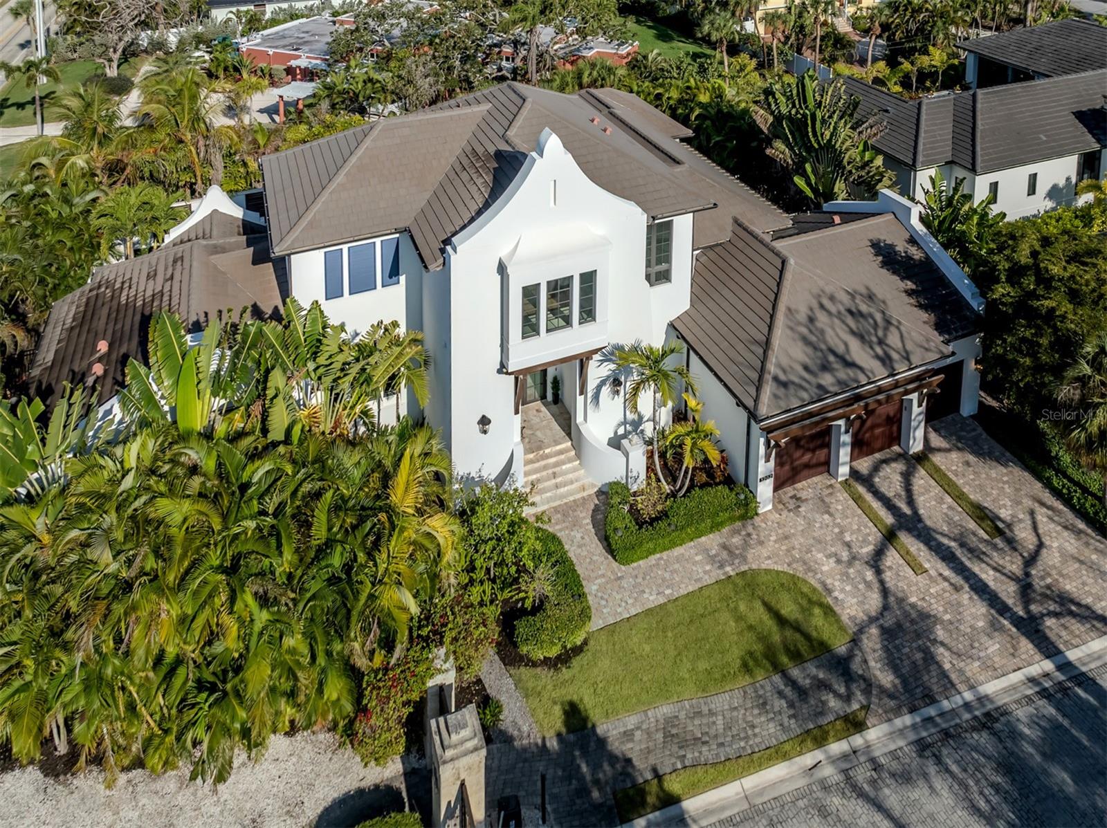 One or more photo(s) has been virtually staged. Nestled within the exclusive gated Siesta Key waterfront enclave of Spice Bay, home to just 14 residences, The Somerset by London Bay Homes defines the pinnacle of coastal contemporary luxury with distinctive West Indies architecture. This two-story, four-bedroom estate harmonizes seamlessly with its lush tropical surroundings, offering serene garden views framed by palms and vibrant flowering landscapes. Just a short stroll from the home, a fully equipped, privately assigned dock along Little Sarasota Bay provides effortless boating access, featuring a 14,000-lb boat lift at the pier’s end.

View the immersive 3D Interior Tour One. Spanning more than 5,000 square feet of air-conditioned living space, the estate is designed for both elegance and effortless entertainment. Expansive sliding glass walls open the great room to the pool deck and covered outdoor living area. French oak flooring and silver-toned designer lighting unify the interior, connecting the dining room, gourmet kitchen, study, and master suite with a refined, cohesive flow. A hidden entry room—currently housing a Control 4 home automation system—offers the potential for a future elevator while controlling lighting, music, and security throughout the home.

Exquisite millwork enhances the interiors, including beadboard, custom built-ins, and architectural beams along the entry stair wall, great room media feature, and gallery leading to the master suite. Floating beams and polished nickel pendant lighting highlight the kitchen and dining area, while a dramatic pyramid ceiling elevates the master bedroom. The study, with its beamed ceiling and pool deck access, opens via double doors for privacy and elegance.

The chef’s kitchen is outfitted with Pompeii white mist quartz countertops, a smoked stiletto tile backsplash, an oversized apron-front breakfast bar, and seamless access to the wine room and butler’s pantry. The dining area flows to the alfresco living space, complete with a fully equipped outdoor kitchen and a dedicated full pool bath. Upstairs, a loft and family room are joined by two guest suites and a fourth bedroom, offering private accommodation for visitors which includes a convenient washer dryer closet.

The master suite overlooks the pool and outdoor fireplace and features a private sitting area. Its luxurious bath includes emerald quartz dual vanities, a polished nickel chandelier, a beamed ceiling, and a freestanding soaking tub beneath a picture window. 

Outdoor living is elevated with a motorized retractable screen, covered lounge and dining area, and a custom Bahama blue linear pool with sun shelf, spa, raised glass-tiled wall with bronze scuppers, and built-in planter. A sun deck, waterfall feature, mosquito misting system, and nearby fireplace create a serene, resort-style experience in complete privacy.

The award winning white powdery sands Siesta Key beach, restaurants and fun shopping are a short three miles away. Quick access to downtown Sarasota with entertainment, dining and cultural options.

Additional amenities include a three-car air-conditioned garage with motorized storage and bike lifts, a 24kW whole-house Generac generator connected to natural gas, fenced in pet exercise area and irrigation supplied by a private on-site well.