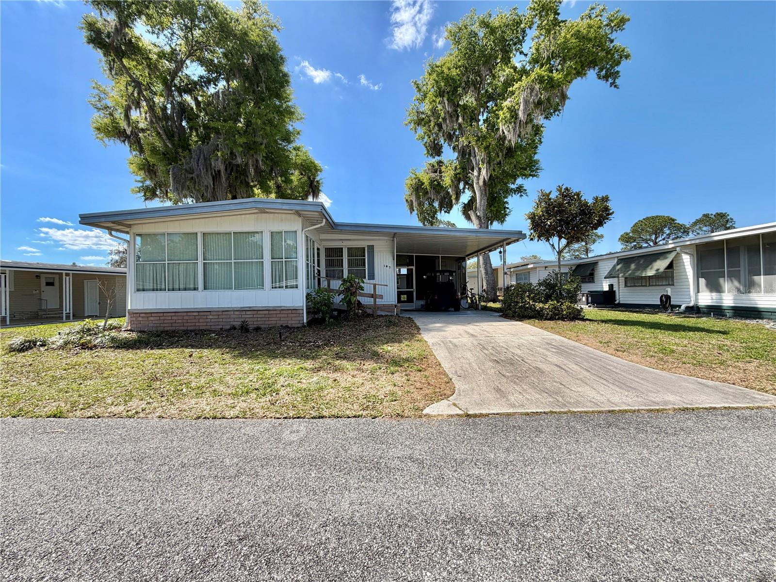 Welcome to 167 Jacaranda, a charming and thoughtfully updated 2-bedroom, 2-bath home offering comfort, style, and easy Florida living in a well-designed 1,008 square feet. Step inside to discover a spacious living and dining area, perfect for both relaxing and entertaining. Beautiful laminate flooring flows seamlessly throughout, creating a warm and cohesive feel. The dining area is enhanced by beautiful built-in cabinetry, providing both character and convenient storage or display space. The fully equipped kitchen features upgraded appliances and modern cabinetry, making it both functional and inviting for everyday living or entertaining. The spacious guest bathroom includes a full tub, perfect for relaxation, while the primary suite offers a walk-in shower and an upgraded toilet for added comfort and convenience. Enjoy the Florida lifestyle year-round in the enclosed screen room located just off the carport, an ideal spot for morning coffee or evening unwinding. Accessibility has been thoughtfully considered with a wheelchair ramp leading to the Florida room, enhancing ease of entry. Additional updates include a membrane roof and HVAC system installed in 2020 offering peace of mind for years to come. This home blends practical upgrades with cozy charm, ready for you to move in and enjoy...............Hawthorne at Leesburg is an active, resident owned, 55+ cooperative, waterfront, gated community, with beautifully landscaped grounds, lakes with illuminated fountains and a relaxing and comfortable gazebo. The affordable monthly maintenance fee of $397 includes water, sewer, lawn mowing, private emergency services and storage space for recreational vehicles, boats, trailers and much more! The beautiful clubhouse is complete with a full-time program coordinator, more than 100 different activities and seating for 550. It has a hospitality lounge, card rooms, craft rooms, billiard room, fitness center, library, fine arts room and many more. There is excellent fishing, outdoor geo-thermally heated pool and two enclosed therapeutic pools. Hawthorne boasts a private marina monitored by an electronic security system with over 120 boat slips and access to the Harris Chain of Lakes and beyond.