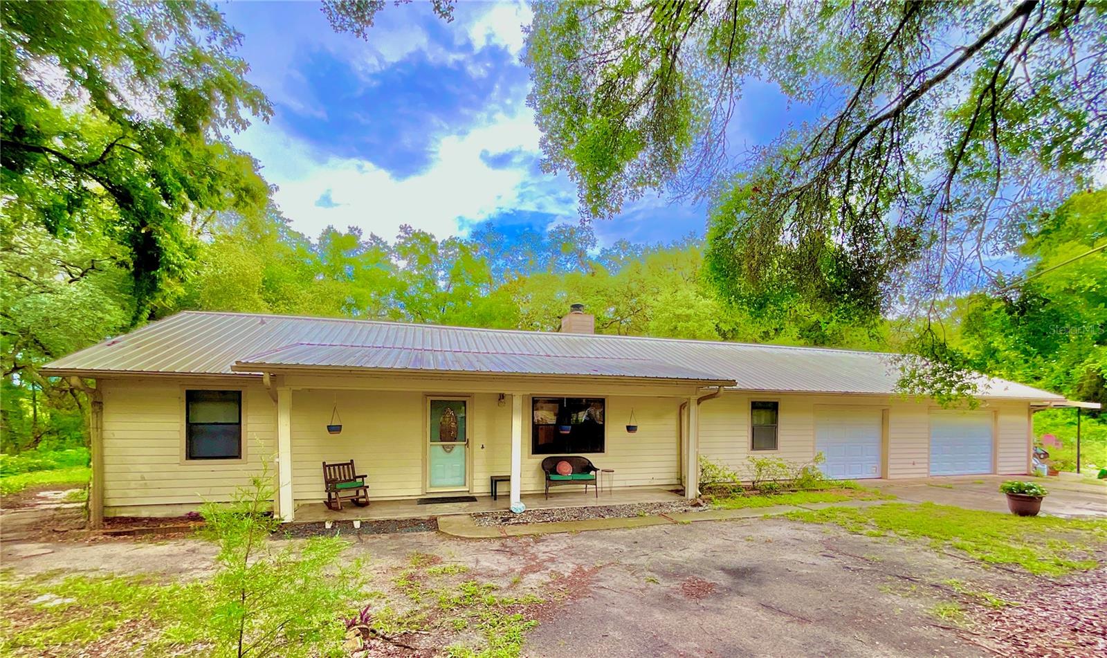 Welcome to your own private homestead retreat! Nestled beneath a stunning canopy of mature trees on more than 5 picturesque acres along the shores of Oldfield Pond, this charming 3-bedroom, 2-bath home offers a rare blend of privacy, natural beauty, and agricultural potential. The property is already flourishing with numerous fruit trees, blueberry bushes, and an established vegetable garden, creating an ideal foundation for a thriving food forest, hobby farm, or sustainable homestead. Zoned AR, the property also allows for limited livestock and farm animals. Conveniently located just minutes from Keystone Heights and historic Melrose, and within approximately 30 minutes of Gainesville, Starke, Palatka, Ocala, and Middleburg, you'll enjoy peaceful country living with easy access to surrounding communities. The home features approximately 1,830 square feet of heated and cooled living space and over 3,180 square feet under roof, including a spacious 780-square-foot garage, a one-car carport, a covered front porch, an enclosed sunroom / versatile flex room complete with a bar. Inside, the split-bedroom floor plan offers both functionality and comfort. The galley-style kitchen is equipped with stainless steel appliances installed in 2021, granite countertops, wood cabinetry, and ceramic tile flooring. The spacious living room features a cozy wood-burning fireplace and flows seamlessly into the dining area. The owner's suite includes ceramic tile flooring, a walk-in closet, and a beautifully appointed bathroom with a walk-in shower featuring dual shower heads. Two additional bedrooms with wood-look vinyl plank flooring and generous closets are located on the opposite side of the home, along with a guest bathroom offering a tub/shower combination. Beautiful views of the property can be enjoyed from most rooms, while underground utilities and an irrigation system serving the area around the home add convenience and functionality. This unique property offers endless opportunities for gardening, farming, recreation, and enjoying the natural Florida landscape.