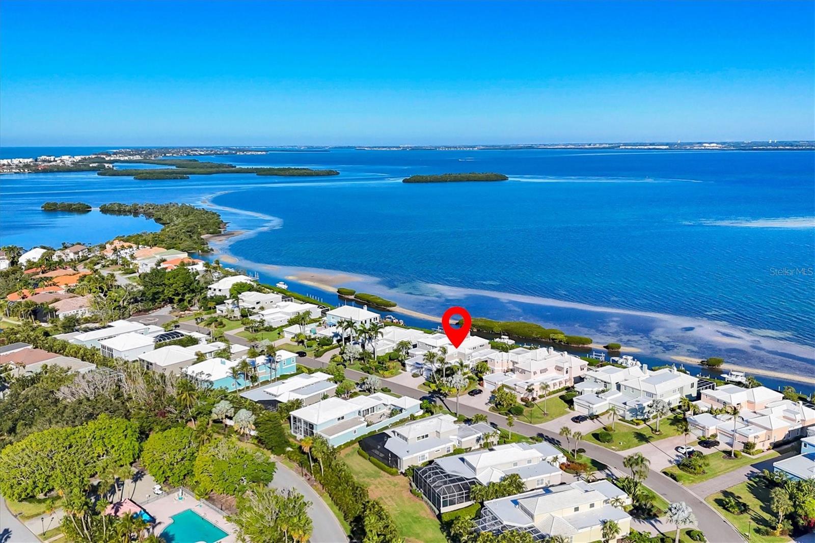 This spectacular direct bayfront residence is offered fully furnished and showcases a thoughtful, top-to-bottom transformation embodying refined coastal luxury. With panoramic views across Sarasota Bay and a deep-water dock equipped with a lift, this four-bedroom home is a true boater’s retreat, offering effortless access to the Bay and the Gulf of Mexico beyond. Every detail has been carefully curated, beginning with new oak hardwood flooring throughout and impact-rated windows and sliding glass doors that bathe the interiors in natural light. Recent enhancements include freshly painted interiors and exterior, a newer roof (2022), and fully updated electrical and plumbing systems—providing both peace of mind and modern efficiency. Spanning nearly 3,200 square feet, the open-concept living area is crowned by soaring cathedral ceilings, creating a sense of volume and airiness. A dramatic fireplace flanked by custom built-in shelving anchors the space, while floor-to-ceiling glass sliders open seamlessly to the expansive bayfront pool deck, blurring the line between indoor and outdoor living. The chef’s kitchen is a showpiece, designed for both beauty and function. Highlights include a waterfall-edge island with bar seating, quartz countertops, brand-new high-end appliances, custom shaker cabinetry with glass accents, a designer tile backsplash, and elegant pendant lighting—perfect for entertaining or everyday enjoyment. The reimagined two-story floor plan places the primary suite in a coveted bayfront position on the main level, with sliding glass doors opening directly to the patio and water beyond. The spa-inspired en-suite bath features a luxurious soaking tub, glass-enclosed shower, and contemporary finishes. A secondary guest suite and a versatile bedroom—currently styled as a den with dual closets—complete the main level, offering flexibility for guests, work, or relaxation. Upstairs, an additional private guest suite provides serene water views and exceptional privacy for overnight visitors. Outdoor living is equally impressive, featuring a brand-new summer kitchen, newer heated swimming pool, and an expansive pavered deck ideal for entertaining or savoring bay breezes at sunset. A walk-down leads to the private dock, where direct deep-water access awaits Located within the gated enclave of Corey’s Landing in the highly desirabe Bay Isles community, residents enjoy a maintenance-free lifestyle with exceptional amenities. Just steps from the home are community tennis courts, while across the street, a heated pool and spa offer a perfect gathering place for neighbors and friends. Owners also enjoy PRIVATE ACCESS TO THE BAY ISLES BEACH CLUB, where miles of pristine Gulf-front beach are just a bike ride or leisurely walk away. World-class dining, boutique shopping, and cultural attractions are all close at hand, with St. Armands Circle, Lido Beach, and downtown Sarasota only minutes away. This is a rare opportunity to experience the very best of bayfront living on Longboat Key—where luxury, lifestyle, and location converge.