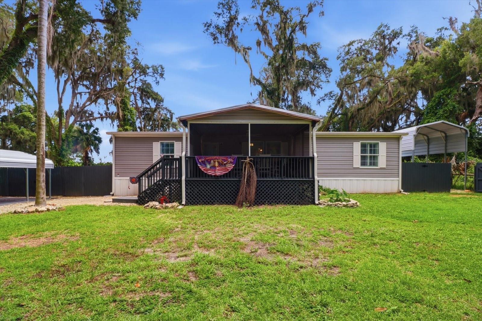 Welcome home to this beautifully maintained 2023 manufactured home offering approximately 1,456 square feet of comfortable living space on a generous 0.34-acre lot. Featuring 3 bedrooms and 2 bathrooms, the open-concept floor plan provides a bright, inviting living area that flows seamlessly into the spacious kitchen and dining area—perfect for everyday living and entertaining. Custom composite interior window shutters add to the appeal. Start your mornings or unwind in the evenings on the large front deck, thoughtfully screen enclosed from top to bottom, including screening underneath the deck to help keep insects out while allowing you to enjoy Florida's outdoor lifestyle in comfort. The split-bedroom layout provides privacy for the primary suite complete with custom tile step in shower and huge walk-in closet, while the expansive homesite offers plenty of room outside for RV or boat parking, gardening, or future outdoor amenities. Property is fenced with solar powered, coded gate and cross fenced for added privacy out back. Double gates allow convenient access to the back yard which features 2 sheds. Metal shed provides ample storage for garden tools while the 10 x 16 wood shed with power makes for a great work shop. Home is wired to accept a portable generator with connection outlet under rear deck. Conveniently located near shopping, restaurants, medical facilities, lakes, public boat ramps, and the many recreational opportunities Citrus County has to offer, this move-in-ready home delivers modern comfort, peaceful surroundings, and plenty of outdoor space to enjoy. And for added peace of mind, a transferrable manufacturer warranty until August of 2029 is available. Call and schedule your viewing today!