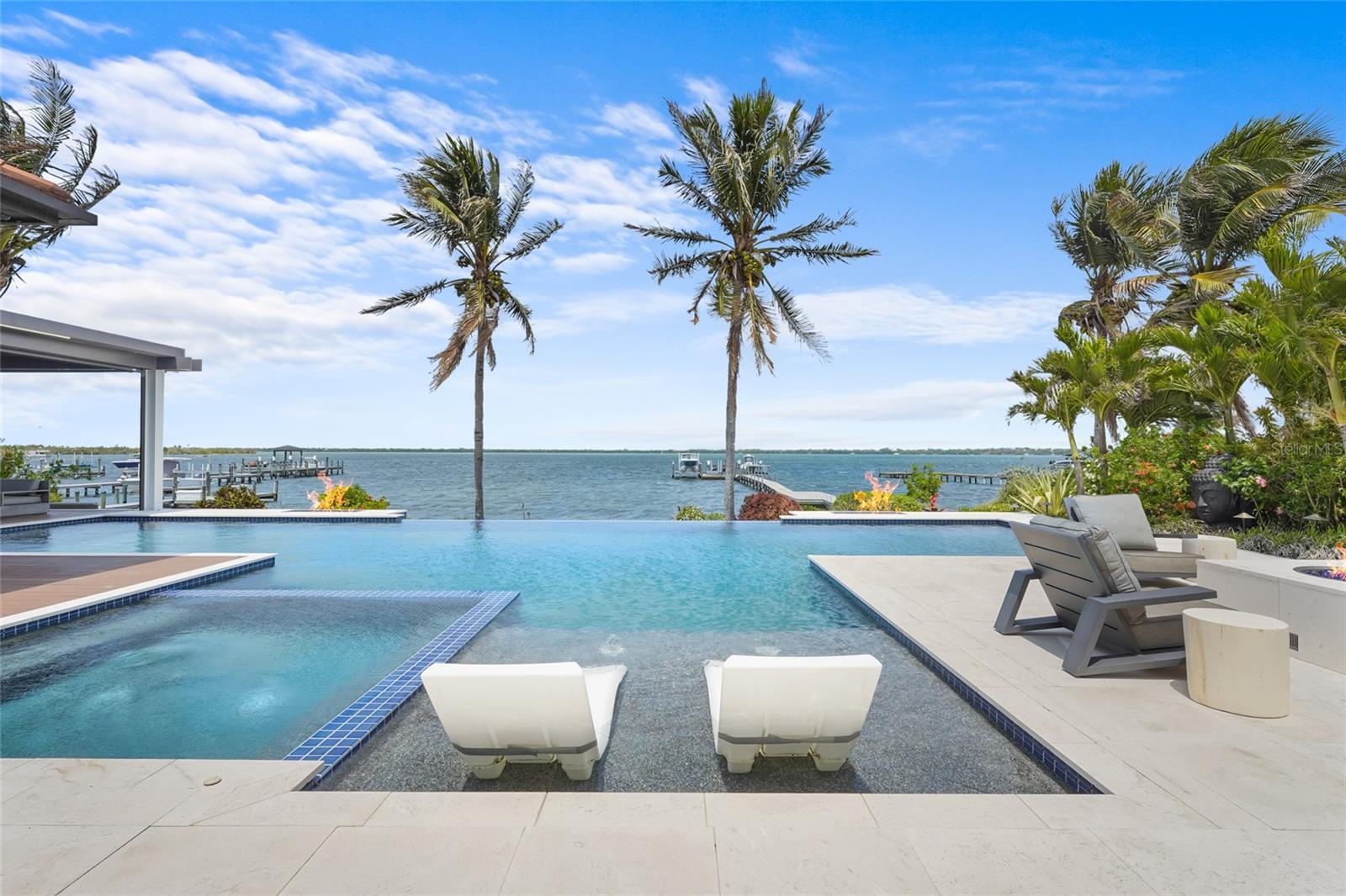 A rare waterfront estate along the Manatee River.
Set on a private homesite with expansive water views stretching toward the Skyway Bridge, this
property offers a unique combination of land, water frontage, and open water views. From sunrise
reflecting across the river to evening sunsets along the horizon, the setting is centered around the
water.
The first floor is designed for a seamless blend of living and entertaining, featuring a primary suite
with water views and a spa-like en-suite bathroom with a walk-in shower overlooking tropical
greenery and a soaking tub positioned near large windows. Two additional bedrooms and two and a
half bathrooms complete the level. Formal living and dining spaces—including a dining room with
wine wall, a living room with fireplace, and a custom study with rich wood built-ins and West
Indies-inspired architectural detailing—flow effortlessly into an expansive family room overlooking
the water. At the center of the home, a high-end kitchen anchors the living space, opening to the
main areas where walls of glass frame the water beyond and create a natural gathering point.Upstairs, a loft-style en-suite retreat offers a sense of privacy and flexibility, complete with custom
wall cabinetry, a full bathroom, walk-in closet, and access to a private balcony with water
views—well suited for guests or additional living space.
Outdoor living is thoughtfully arranged to maximize the waterfront setting. A covered patio features
an outdoor kitchen and grilling area, complemented by an outdoor shower. Just beyond, the
infinity-edge pool and integrated spa are positioned along the water’s edge, creating a seamless
visual connection to the water. A sun shelf and generous deck space provide multiple areas for
lounging and entertaining, all oriented toward the expansive views.
For boating enthusiasts, a deep-water dock with T-head platform, 16,000-pound boat lift, and jet ski
lift extends into open water with access to Tampa Bay and the Gulf of Mexico. A new seawall
lines the waterfront.
The approach is enhanced by an extended pavered driveway with multiple parking areas,
complemented by a three-car garage, providing generous space for vehicles and guest arrivals.
The home has been extensively updated, including a new roof, generator, well system, HVAC
components, hurricane-rated window and transom installation, refinished and expanded outdoor
living areas with updated lighting and landscaping, and a renovated outdoor shower. Interior
improvements include new flooring, custom built-ins, renovated bathrooms, upgraded closet
systems, and smooth-finish walls throughout, along with refined design details.
Located near Robinson Preserve, De Soto National Memorial, the
property offers convenient access to trails, kayaking, preserved land, and local markets. Gulf
beaches, including Anna Maria Island and Longboat Key, are approximately 6–8 miles away,
providing easy access to coastal destinations while maintaining a private residential setting.