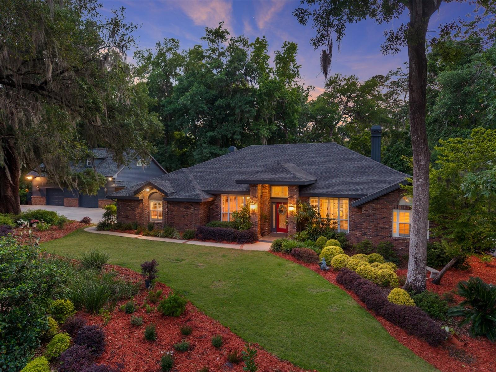 Some homes are built. Others are engineered to endure for generations. Welcome to Richmond, where timeless craftsmanship meets one of Gainesville's most remarkable private settings. Constructed with FULL STRUCTURAL BRICK, this is not a conventional wood-framed home with brick veneer. True structural masonry construction is rarely found in residential homes today and represents a level of durability, strength, and craftsmanship that is increasingly difficult and significantly more expensive to replicate. Positioned on 1.46 private acres overlooking a scenic ravine and framed by majestic live oaks, the property offers a setting that feels secluded while remaining just minutes from the best of northwest Gainesville. Beyond the home itself, the owners have created MORE THAN $200,000 of value IN PROFESSIONAL LANDSCAPING AND HARDSCAPING, transforming the grounds into a private resort. Stone walkways, outdoor gathering spaces, mature landscaping, automatic landscape lighting, and thoughtfully designed entertaining areas create an environment that is every bit as exceptional as the residence itself. Comfort and efficiency were equally prioritized with FULL ISONENE SPRAY FOAM INSULATION THROUGHOUT THE DETACHED GARAGE APARTMENT, providing outstanding energy efficiency, quieter interior spaces, and year-round comfort. Designed by renowned architect Tom Hunt, the home blends timeless architecture with thoughtful functionality. Soaring ceilings, extensive crown molding, engineered hardwood flooring, plantation shutters, multiple fireplaces, and expansive windows fill the home with warmth, character, and natural light. The chef's kitchen serves as the heart of the home, featuring custom Busby cherry cabinetry, a six-burner Thermador range, generous preparation space, and seamless flow into the living and entertaining areas. The primary suite offers its own private retreat with a fireplace, sitting area, and direct access to the outdoor living spaces. Outside, entertaining becomes an experience. Relax beside the screened pool overlooking the ravine, unwind in the hot tub, gather around TWO OUTDOOR FIRE PITS, including one gas and one traditional wood-burning, enjoy evenings beneath the lighted gazebo, or rinse off after a swim in the outdoor shower. Every space was intentionally designed to bring people together while embracing the natural beauty surrounding the home. The detached garage apartment offers outstanding flexibility for extended family, guests, a private office, multigenerational living, or future income potential. Luxury is often measured by finishes. True quality is measured by how a home was built. For the buyer who appreciates exceptional construction, enduring craftsmanship, thoughtful design, and investments that cannot simply be duplicated, this Richmond estate represents a rare opportunity.