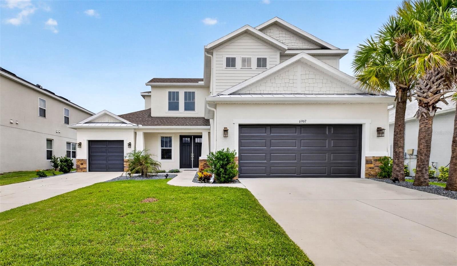 One or more photo(s) has been virtually staged. Welcome to Talamore, a village within Wesley Chapel’s sought-after WaterGrass community. Step inside this beautifully upgraded two-story home offering 5 bedrooms, 4 full bathrooms, 1 half bathroom, 3,475 sq ft, and a total 3-car garage with both a 2-car garage and a separate 1-car garage. The grand foyer sets the tone with soaring ceilings, a modern halo chandelier, custom cable stair railing, 8-foot doors, recessed lighting, LVP flooring throughout, and no carpet anywhere in the home. The main living area is filled with natural light and features a tray ceiling with crown molding, a striking accent wall, and an open connection to the gourmet kitchen. The kitchen is designed for everyday function and style with quartz countertops, a large island, 42-inch shaker cabinets with crown molding, new backsplash, island pendant lighting, upgraded cabinet hardware, an LG refrigerator with craft ice and sneak peek window, a built-in cooktop, a separate oven, and a microwave. The main bedroom is located downstairs just off the living room and includes a tray ceiling, accent wall, walk-in closet, and an en-suite bathroom with upgraded lighting, faucets, shower hardware, soaking tub, dual vanities, and a double-entry shower with dual shower heads. Also downstairs, you will find a bedroom or office with its own en-suite bathroom, a powder bathroom, a laundry room with GE washer and dryer on pedestals, and a convenient drop zone near the garage. Upstairs, the custom modern staircase leads to three additional bedrooms and a spacious bonus room, with the largest upstairs bedroom also featuring an en-suite bathroom. Each bedroom includes a ceiling fan, and the bathrooms have updated fixtures for a clean, modern finish. The fully fenced backyard is just as impressive with updated landscaping, a full-length French drain system, and an extended decorative concrete patio that stretches approximately 15 feet from the triple sliding doors, creating a great outdoor space to relax or entertain. Located in the sought-after WaterGrass community, residents enjoy access to resort-style amenities, including a clubhouse, pools, a fitness center, playgrounds, basketball courts, tennis and pickleball courts, a dog park, open green space, and a golf cart-friendly setting. The location adds even more convenience with Publix at Innovation Springs about 5 minutes away, Watergrass Elementary nearby, and easy access to SR 54, I-75, I-275, The Shops at Wiregrass, Tampa Premium Outlets, Epperson Lagoon, parks, dining, shopping, and everyday essentials. See this beauty in person. Schedule your private tour today.