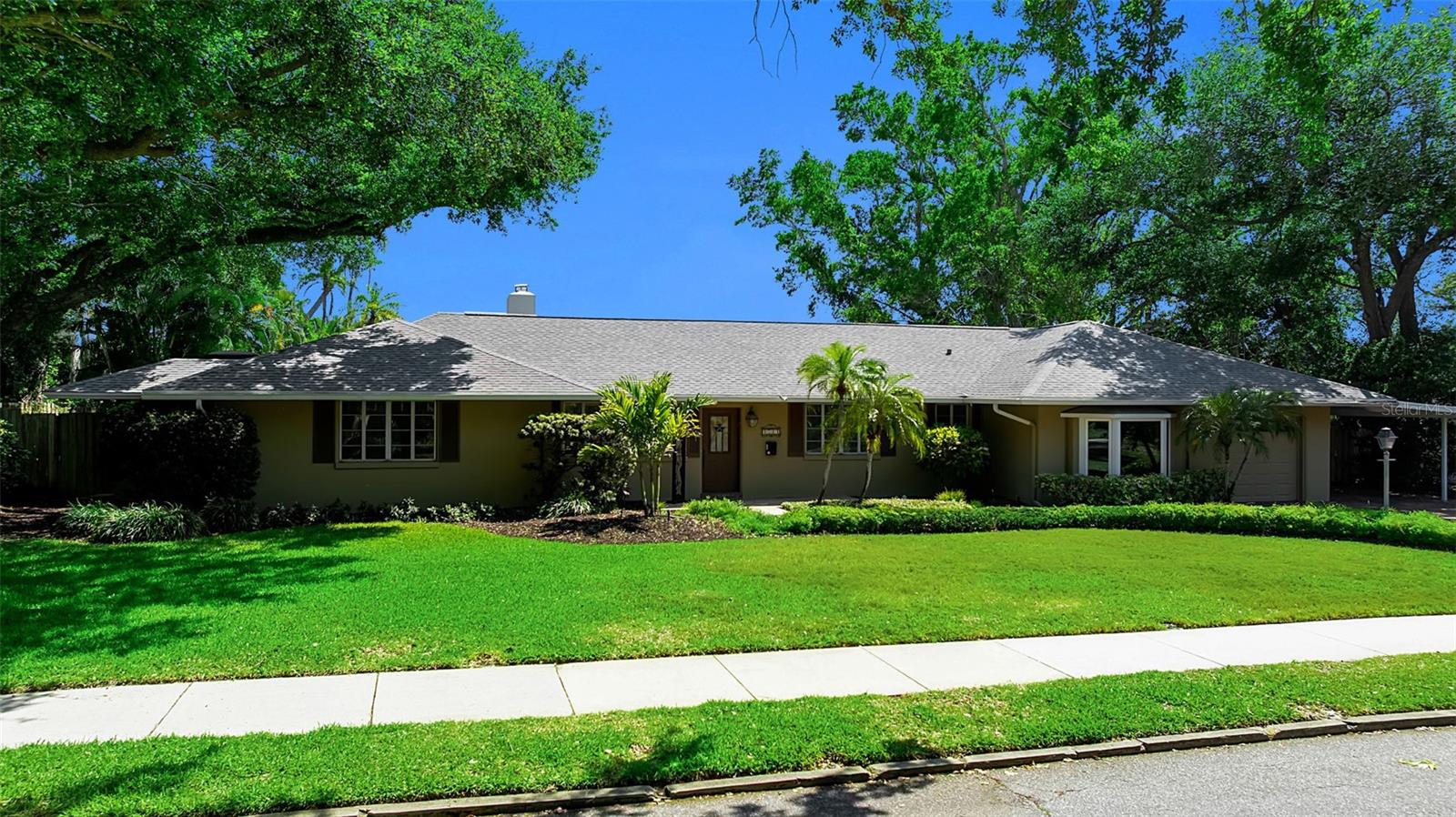 Virtually Staged. Tucked beneath a canopy of mature trees in one of Sarasota’s most coveted neighborhoods, 1714 South Drive presents a rare opportunity to secure a prime homesite in Cherokee Park, West of the Trail and moments from the very best of Sarasota living. Set on a beautifully established lot with lush, mature landscaping, a paver driveway, and a combination of garage and carport parking, the property offers an immediate sense of privacy and presence. Inside, the home unfolds with a surprisingly expansive footprint and a floor plan that captures natural light throughout. A welcoming entry with a leaded stained-glass door opens to multiple living spaces, including a living room with a wood-burning fireplace, custom built-ins, and distinctive Saltillo tile flooring, alongside a light-filled family room wrapped in windows with views of the pool and direct access to the lanai. The dining room, positioned with a bay window overlooking the pool, connects seamlessly to the kitchen, which features granite countertops, glass-front cabinetry, a center island with cooktop, and a breakfast nook with access to a private side deck. The layout offers flexibility with multiple bedroom and office options, including a front bedroom or office with a wall of windows and an in-wall safe, and a private guest suite with its own bath showcasing vintage turquoise tile and retro detailing. A secondary guest bedroom includes built-in workspaces and shelving, ideal for dual office use or creative space. The primary suite is tucked privately toward the rear of the home, offering direct access to the lanai, abundant natural light, and a spacious bath with dual vanities, soaking tub, walk-in shower, and skylight above. Additional spaces include a bonus room off the garage with bedroom conversion potential, a pool bath, and a separate flex space off the lanai with wood-paneled walls and its own mini-split system, ideal for a studio, gym, or additional lounge. Outdoors, the home continues to deliver with an oversized, caged pool and covered lounging areas, surrounded by mature landscaping, stone walkways, and a fully fenced yard. An existing outdoor kitchen structure and multiple access points from the home create a true indoor-outdoor flow that aligns perfectly with Sarasota’s year-round lifestyle. What truly elevates this property is its location. Just moments from the shops and restaurants of Southside Village or downtown Sarasota’s waterfront, cultural venues, and marina. It is close to Sarasota Bay and just a short drive to Siesta Key’s north bridge. This is a setting that defines convenience and coastal luxury. Cherokee Park remains one of the most desirable addresses in Sarasota, and 1714 South Drive offers the rare combination of location, lot, and layout, an exceptional opportunity in the heart of Sarasota.