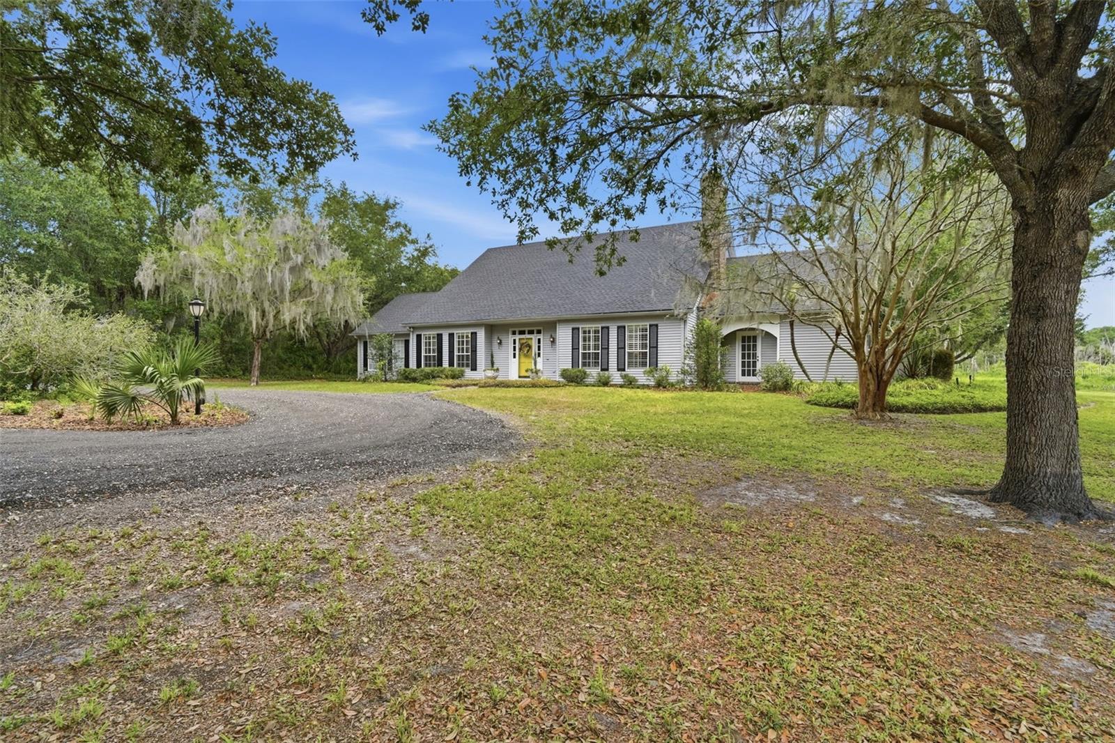 Country living, two miles from the center of downtown DeLand.
Nestled on 2 private acres with peaceful pond views, this custom Cape Cod-style home offers the perfect blend of timeless charm, luxury, and functionality. Approaching through a gated neighborhood entrance along an 
all-weather access lane, the circular driveway creates a grand first impression. The new roof, oversized carport with RV parking out back, and additional storage shed provide convenience and flexibility for all your lifestyle needs.
Designed for both relaxing and entertaining, the outdoor living spaces are truly exceptional. Enjoy the private saltwater pool surrounded by a large screened lanai patio perfect for year-round Florida living, along with a beautiful pergola ideal for outdoor grilling and dining, gatherings, or simply unwinding while taking in the tranquil surroundings.
Inside, the warm and inviting living room features  beamed ceilings, a stunning fireplace, built-in shelves, and rich Brazilian cherry hardwood floors that add elegance and character throughout the home. The dedicated office with wall-to-wall shelving creates the perfect work-from-home space, library, or hobby room.
The open kitchen is both functional and stylish with stainless steel appliances,
plentiful cabinet storage, walk-pantry, decorative backsplash, beer and wine fridges, and a 7’x3’ center island with seating, making it the heart of the home for entertaining family and friends.  A breakfast area flows from the kitchen, with a view to the pool patio and outdoors.


The main dining  area adjoins the living room, and is filled with natural light from oversized windows overlooking scenic backyard views. The dining area flows into a spacious sun room with built-in shelving and room for relaxing and/or exercise.
The large primary suite offers a private retreat with French door access to the front and back of the house, a spacious walk-in closet, and a beautifully designed en suite bathroom featuring double sinks, a relaxing deep Japanese soaking tub with jets and a rain shower head. Step outdoors for a secluded deck with an all-season, instant-heat shower. The additional upstairs bedrooms are generously sized with large double closets and plenty of room for guests or family.
Surrounded by natural beauty and offering exceptional privacy, this one-of-a-kind property combines custom craftsmanship, inviting living spaces, and resort-style outdoor amenities in a truly picturesque setting.
