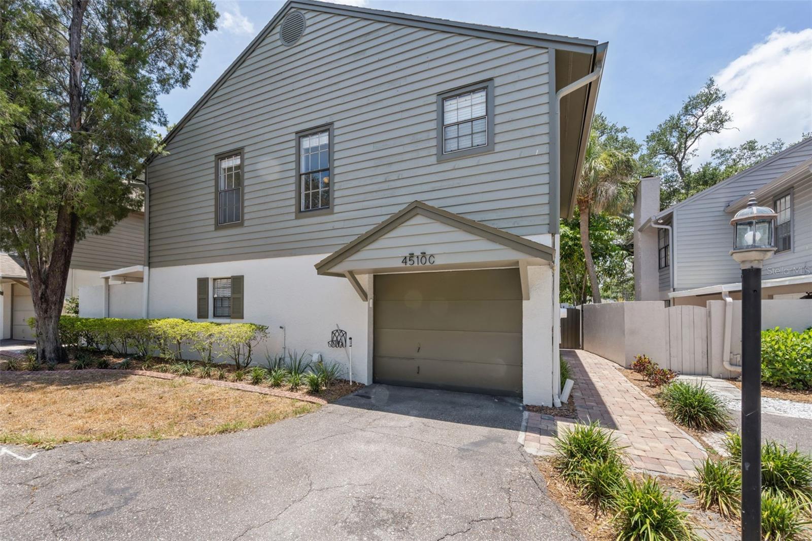 RARE SINGLE-FAMILY STYLE, STAND-ALONE 3 BEDROOM, 2.5 BATH CONDO in the heart of Westshore! Offering the privacy and feel of a single-family home, this beautifully updated residence features a LARGE PRIVATE TROPICAL BACKYARD and an expansive SCREENED LANAI, creating the perfect indoor-outdoor living space for relaxing or entertaining.  Step inside to soaring two-story ceilings in the light-filled living room, complete with a charming WOOD-BURNING FIREPLACE and panoramic views of the lushly landscaped backyard. The main level showcases NEW VINYL FLOORING throughout, while the upstairs has been updated with newer flooring.  The kitchen is well-appointed with UPDATED GRANITE COUNTERTOPS, NEWER STAINLESS STEEL APPLIANCES, a BOSCH DISHWASHER, generous storage, a closet pantry, and a convenient pass-through to the dining room.  Upstairs, the spacious primary suite offers private balcony access overlooking the serene backyard retreat. The PRIMARY BATH HAS BEEN BEAUTIFULLY UPDATED, featuring a NEW WALK-IN SHOWER (2025), updated plumbing, and a custom walk-in closet organization system. Additional bathroom updates add even more value.  Major improvements provide peace of mind, including: INTERIOR PAINT (2025), NEW RAIN BIRD IRRIGATION SYSTEM (2025), NEW GARAGE DOOR OPENER (2025), NEW ROOF (2020), A/C UNITS (2017), ELECTRICAL PANEL (2018), WATER HEATER (2019). Bretton Woods is a small, tucked-away oasis offering the benefits of condominium ownership with the privacy of semi-detached living.  Located in the highly sought-after Plant High School district, this prime Westshore location offers easy access to shopping, dining, downtown Tampa, the airport, and all the conveniences of South Tampa living.