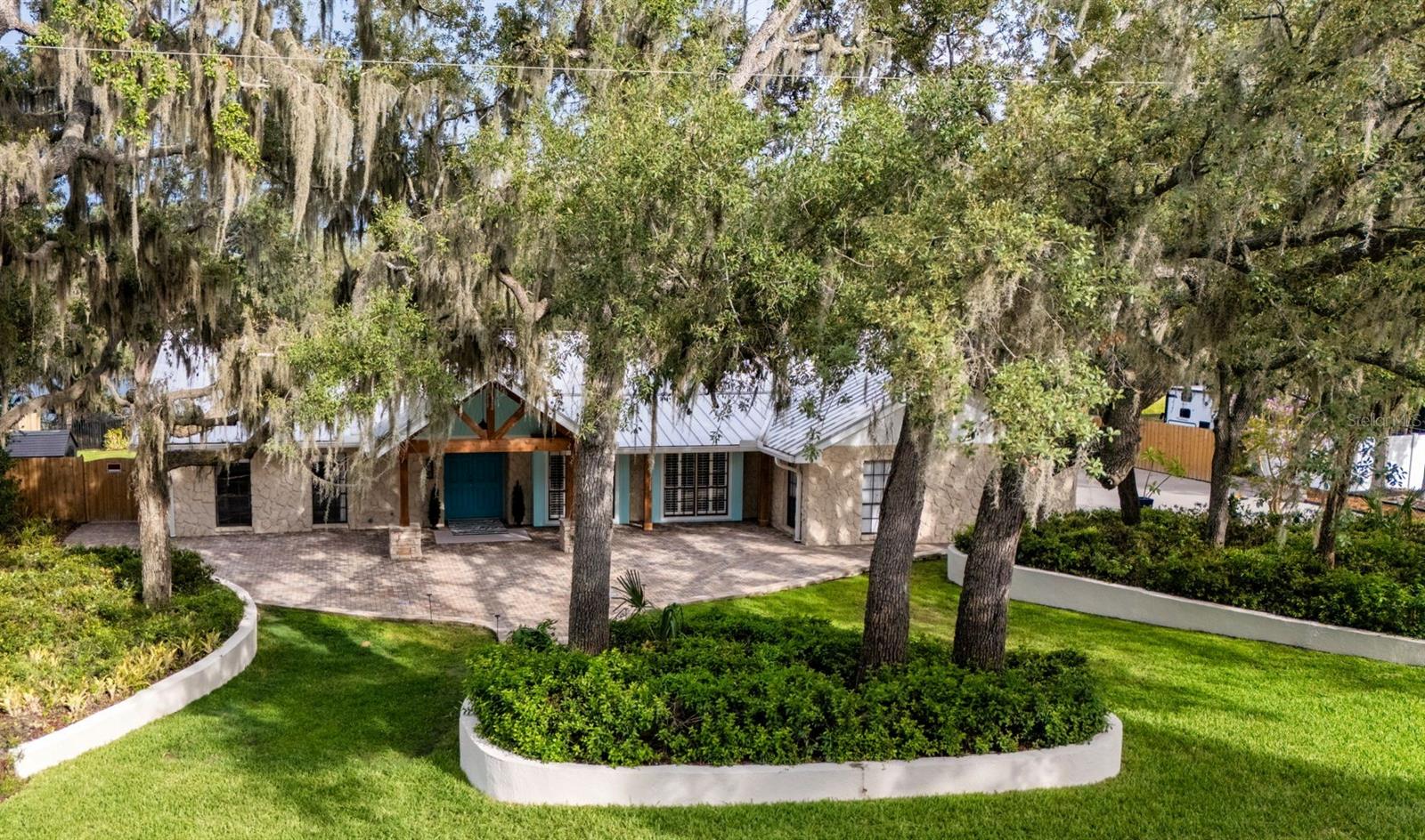 Over 1 Acre Lakefront Home with Dock, Pool, and Exceptional Outdoor Living
Welcome to this beautifully updated lakefront home situated on over 1 acre, more or less, with a private dock, no CDD, and low HOA fees. Designed for entertaining and relaxed Florida living, this spacious 4-bedroom, 3-bath home also features a dedicated office, laundry/mudroom, oversized garage, deep pool, and multiple outdoor entertaining areas.
A large covered front porch with cedar beams and stacked stone accents creates a warm and inviting entry. Inside, you are welcomed by a spacious foyer, engineered hardwood flooring, tile throughout, no carpet, and abundant closet space. The flexible living room offers multiple possible uses, including a game room, formal dining space, or additional sitting area.
The updated open-concept kitchen features a bright marble-topped island, solid marble backsplash, stainless steel appliances, and excellent flow into the great room and dining area. The great room is a true centerpiece of the home, complete with a stacked stone wood-burning fireplace, custom built-ins, and recessed sliding glass doors that open to the outdoor living spaces.
All bathrooms have been tastefully updated, and every bedroom includes a walk-in closet customized by California Closets. The oversized primary suite offers recessed sliding glass doors for indoor-outdoor living, plus two large separate walk-in closets. The updated primary bathroom features a walk-in shower with a rolling glass barn door, Clearview glass coating, a free-standing soaking tub, Carrara-style tile, custom cabinetry, and a separate water closet.
Outdoor living is where this home truly shines. Fish or lounge on your own personal dock! Enjoy the deep pool, freshly updated pool deck, two attached covered patio areas, screened lanai, outdoor pavered deck, private outdoor shower, fenced side yards, and approximately 5,000 square feet of concrete brick pavers, with hardscape retaining walls, sidewalks, and front courtyard space. Pavered walkways and hardscape provide convenient access around the entire home, with lighted pathways from the pool, outdoor shower directly to the luxurious primary bath.
The home also offers two full laundry setups: one inside the pantry/laundry/mudroom with built-in custom California Closets shelving, and an additional washer/dryer area in the garage, perfect for towels, rugs, pet items, and outdoor gear. The oversized garage and entire driveway feature professional concrete coating with designer flecks for a clean, finished look.
Both side yards are fully fenced and flank the newly updated screened lanai. One side yard includes an outdoor shed that can be used as a playhouse or extra storage, while the opposite side yard features a 10-foot-wide gate opening for easy access to the backyard and dock.
Fish, boat, bird-watch, entertain, relax by the pool, or enjoy beautiful sunrise and sunset views from your own lakefront property. This home offers space, privacy, updates, and true indoor-outdoor living.
CALL  today to schedule your PRIVATE SHOWING.
Furniture, decor, pots, artificial and real plants are for staging only and are not included.
