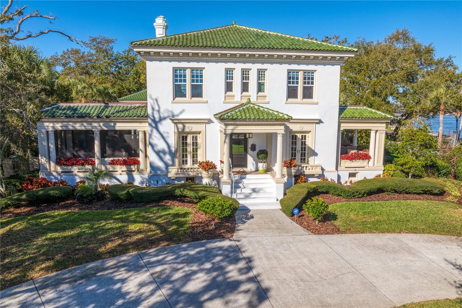 This Palm Beach style home is one of St. Petersburg's most iconic properties where everyone slows down to admire the white columned and pediment facade as the grand entrance to North Shore Dr NE in the Historic Old Northeast.  Situated on over a half acre of land along with 360ft of open waterfront consisting of FOUR water lots (8ft water depth and extending 45ft from sea wall) this remarkable property reveals a tropical alley of towering palms and tended flower beds of North Shore Park and the wide boulevard along Tampa Bay. This historic home remains one of the last vestiges of an era, where quiet elegance was the order of the day and now accommodates a more modern and casual lifestyle.  A beautiful and sweeping circular drive leads to an elegant entrance hall and immediately showcases the excellent proportions of each room with 9 1/2 ft high tray ceilings, 8ft windows (all new hurricane windows upstairs and doors,) indoor/ outdoor terraces bringing in daylight to every space and a view of the sparkling waters.  Life here is chic, tropical and upbeat!  A relaxed and open formal living room with white upholstered furniture keeps the room airy yet inviting.  The family room opens with a collapsible door to completely open the space inside and out with a shaded screened terrace overlooking the front gardens and open water beyond.  The dining room, and another dining space on the loggia, overlook the park and bay on one side and the pool and backyard on the other side.  There are 4 bedrooms and 3.5 bathrooms in the main house, each bedroom having magnificent water views.  An added bonus is a full sized basement matching the footprint of the main house. The 60-foot heated lap pool separates the main house from the guest house which is above the 2-car garage.  The guest, in-law or apartment is a one bedroom with living room, kitchen, full bathroom and outdoor screened porch creating another tropical escape.  An additional full pool bath occupies the first floor of the guest house.  A gorgeous white columned wall surrounds the entire property accented with lush shrubbery and trained vines against the white wall.  All new sloped roofs with the highest level of insulation and an essentially brand new green Ludowici tile roof.  Other updates include; all new copper pipes, completely new electrical, new AC units, all new composite dock (35 x 15 to accommodate a boat up to 31 ft) with high speed lift and 13,000 lbs. weight capacity.  Beautiful walkways on each side of the home and behind the property of visual interest are accented with traditional rod iron gates.  A classic rectangle pool with a fountain creating the most soothing atmosphere with palms and OAK trees shading the pool to the west of the house.  This landmark home, at the epicenter of the historic Old Northeast neighborhood, with its brick streets, banyans and mangroves, oaks and palms, is your tropical escape.  It’s a testament to what can be achieved with great taste and style inspired by the natural beauty of this incredible waterside town.