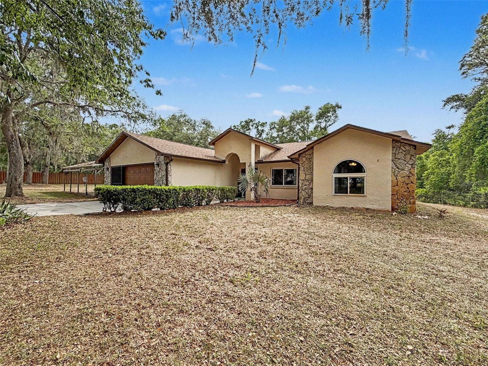 Welcome to your own private Florida retreat in Webster! Situated on a beautifully secluded 1.2 acre lot shaded by stunning mature Florida oaks, this gated and fully fenced property offers the perfect combination of privacy, comfort, and convenience. This home features a brand-new 2026 roof, soaring vaulted ceilings, newer appliances, and granite countertops in the bathrooms for an updated, elegant touch. Not only does this spacious home have a nice-sized living room, it also has a formal dining room and den with a beautiful stone fireplace. Step outside to enjoy the oversized screened-in back porch perfect for relaxing, entertaining, or taking in the peaceful natural setting. Additional highlights include an attached 1.5-car garage, a detached garage for extra storage or workshop space, a large carport for covered parking, and plenty of room to enjoy outdoor living. Conveniently located near I-75, shopping, dining, and local amenities, this property provides peaceful living with easy access to everything you need.