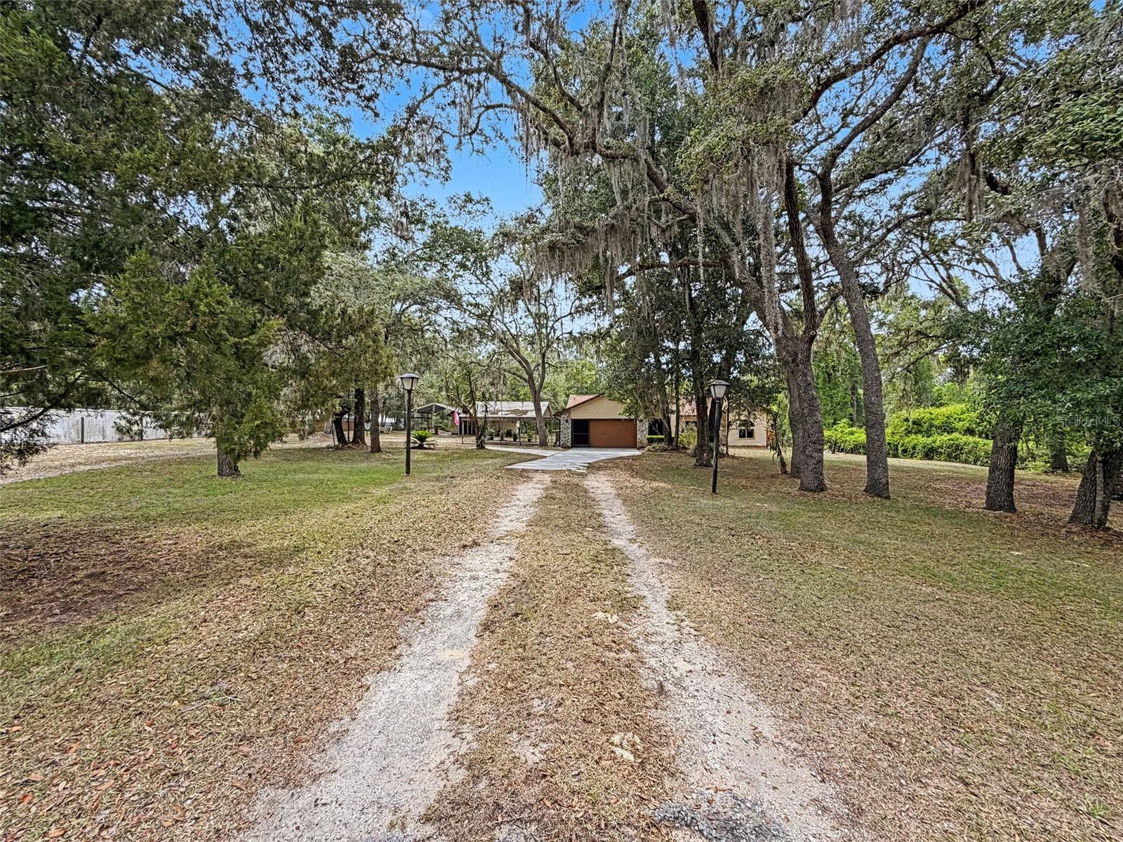 Welcome to your own private Florida retreat in Webster! Nestled beneath majestic mature Florida oaks on a beautifully secluded, gated, and fully fenced 1.2-acre homesite, this property offers the perfect blend of privacy, functionality, and convenience.
Inside, you'll find soaring vaulted ceilings, a spacious living room, a versatile flex room that can serve as a formal dining room, home office, or additional living space, and a cozy den featuring a stunning stone fireplace. The kitchen has been updated with new countertops, a new refrigerator, and a new stove, while the bathrooms feature elegant granite countertops. A brand-new 2026 roof provides added peace of mind.
One of the home's standout features is the incredible 25' x 35' (875-square-foot) screened porch—an exceptional outdoor living space perfect for entertaining, relaxing with family and friends, or simply enjoying the peaceful natural surroundings year-round.
The property also offers an attached 1.5-car garage, a detached garage that's ideal for extra storage or a workshop, a large carport for additional covered parking, and plenty of room for RVs, boats, hobbies, gardening, or simply enjoying your own private slice of Florida.
Conveniently located just minutes from I-75, shopping, dining, and everyday amenities, this unique property offers the tranquility of country living with easy access to everything you need.