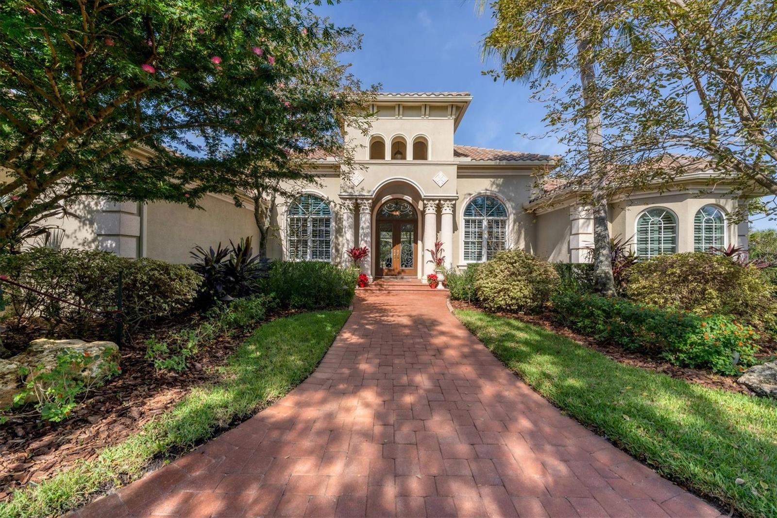 This impressive Pruett Mira Lago III estate home boasts a grand total of over 5,000 square feet of living space. It is perfectly positioned on a three-quarters-acre lot, featuring an extra-wide frontage and an expansive circular driveway. This magnificent residence was meticulously designed and constructed to embrace panoramic views of three distinct fairways: the 1st, 2nd, and 5th holes of the Robert Trent Jr. golf course, all while offering captivating lake vistas. It excels as an ideal residence for both indoor and outdoor entertainment. 

The interior comprises three bedrooms, a library/office adorned with wood floors, and a custom-made "Gothic" style library bookcase equipped with up and down lighting, along with custom shutters. The chef's dream kitchen comes complete with an extra-large pantry. The living room, looks out into the lanai and boasts stunning views of the pool with its water features, lake and golf course.  It features a gas fireplace and seamlessly connects to a formal dining room and a butler's wet bar, catering to your entertainment needs. There's also a room suitable for a piano or a second office. The primary suite offers a generously sized bedroom with an additional area for reading or relaxation.  Two spacious walk-in closets with built-in shelves and drawers connect to an opulent bathroom with two water closets, a walk-in shower, whirlpool tub, and double vanity. One of the closets even features a built-in wall safe. The family room also boasts stunning views of the spectacular pool, lake, and golf course.

Adding to the luxury, an elevator takes you to a sizable upper floor. The second floor of this luxurious home is a haven for entertainment enthusiasts, featuring a spacious and elegantly designed area dedicated to leisure and enjoyment. The centerpiece of this level is a generously sized entertainment space that offers ample room for hosting gatherings, relaxation, and various recreational activities. The crowning jewel of this space is a beautifully appointed balcony that provides breathtaking vistas of the surrounding landscape. With sweeping views that extend beyond the horizon, the balcony becomes a tranquil retreat where one can bask in the beauty of the natural surroundings, making it an ideal setting for both indoor and outdoor leisure.
 
Inside, the residence is adorned with soaring ceilings and crown molding, an abundance of natural light, custom shutters throughout, stone columns, and a harmonious blend of tiled and wood floors, all tastefully complemented by a neutral color palette. The outdoor living space is truly impressive, featuring a well-appointed kitchen and a generously sized caged pool and spa. Clearview lanai screens, arches and up lit columns. Mature landscaping with extensive up-lighting. Spanish barrel tile roof and hurricane resistant windows and sliders throughout. Nestled within The Founders Club, a prestigious golf and country club community spanning 700 acres with 262 home sites, this luxurious property not only offers an exceptional home but also grants access to a plethora of community amenities. Conveniently located in Sarasota, Florida, it provides effortless access to I-75, downtown Sarasota, Gulf Coast beaches, shopping, and a diverse array of dining options, all just minutes away.