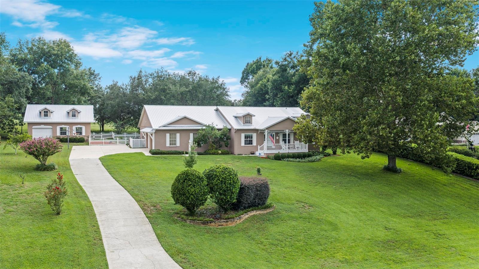Welcome home to this beautifully maintained property where privacy, quality craftsmanship, and versatile living come together on a spacious lot backing to mature trees in Clermont's rolling hills. This custom home features durable steel stud construction, a roof less than one year old, a long winding driveway, and an inviting covered front porch that creates timeless curb appeal from the moment you arrive. Inside, the open-concept layout is warm and inviting, with crown molding adding a polished, elevated touch throughout. The heart of the home is the well-appointed kitchen, featuring granite countertops, stainless steel appliances, custom wood cabinetry, abundant counter space, and a breakfast bar that flows seamlessly into the living and dining areas—perfect for everyday living and entertaining. Abundant natural light and quality finishes add warmth and character throughout. The spacious primary suite offers a peaceful retreat with a sitting area, walk-in closet, plantation shutters, and an updated en-suite bath featuring a garden soaking tub, separate glass-enclosed shower, and dual vanities. Step outside to the rear screened and covered porch overlooking the fully fenced backyard, where mature trees provide privacy and a peaceful setting for morning coffee, quiet evenings, or weekend gatherings. A standout feature of the property is the detached 24' x 30' workshop/garage with a matching metal roof. The main level features a single garage bay and spacious workshop area, while the finished loft/storage level above offers spray foam insulation, plywood flooring, lighting, and endless possibilities for hobbies, storage, or creative workspace. Conveniently located near Clermont's lakes, parks, shopping, dining, and major roadways, this property offers the perfect balance of peaceful country living and everyday convenience. If you've been searching for a home that offers quality construction, exceptional workshop space, and room to spread out, this is one you won't want to miss.