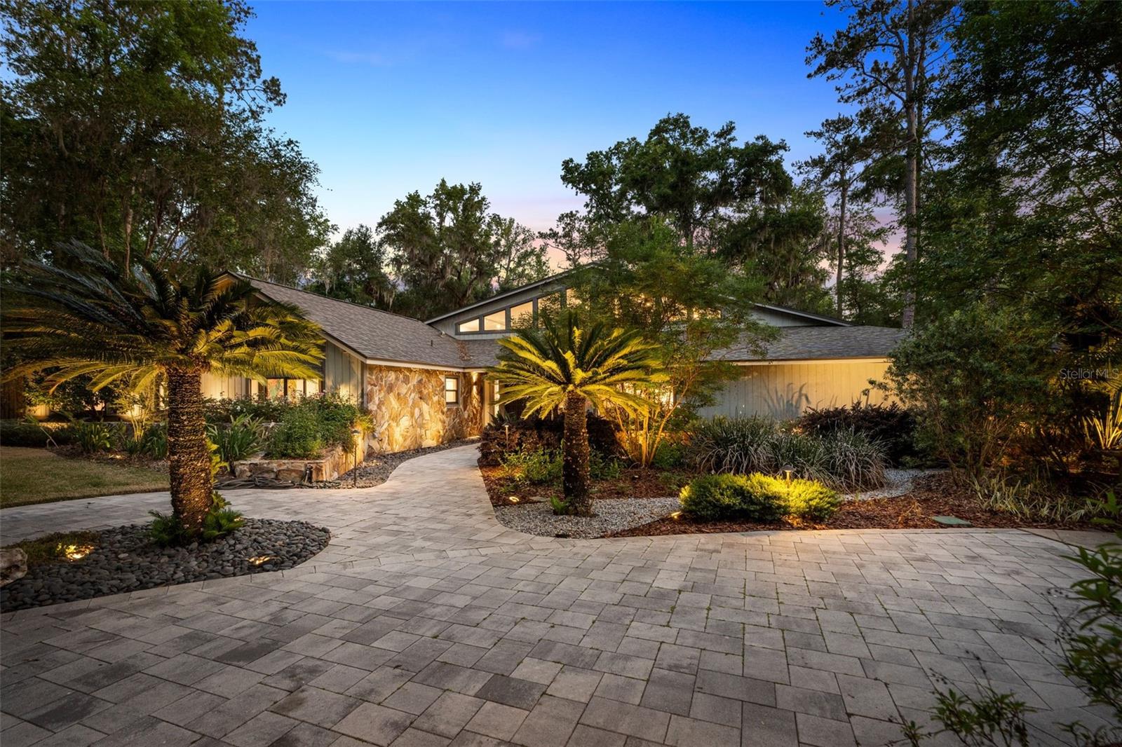 This extraordinary Gainesville estate represents a rare convergence of scale, design, and nearly $1,000,000 in thoughtful, high-end upgrades. Set on two fully fenced acres, every inch of this property has been curated to deliver a seamless blend of modern luxury, privacy, security, and resort-style living.

The transformation begins at the rear of the home, where a former enclosed indoor pool was completely reimagined. The back of the residence was opened and removed to create a stunning outdoor living environment, anchored by a brand-new pool and spa framed within a panoramic screen enclosure. Here, a fully appointed indoor-outdoor kitchen, multiple contemporary water features and fountains, an AstroTurf golf pad, and a dramatic 400,000 BTU gas fire pit create an atmosphere designed as much for grand entertaining as it is for everyday escape. As evening falls, over 180 strategically placed landscape lights bring the grounds to life, while an extensive security camera system provides peace of mind.

Inside, the home is equally impressive. A grand entry reveals a soaring great room with 20+ foot ceilings, centered around a striking concrete fireplace that artfully divides the living spaces. On one side, a sun-drenched living room opens effortlessly to the pool and outdoor kitchen through expansive sliding doors, flanked by oversized transom windows that flood the space with natural light. On the other, a sophisticated wet bar showcases backlit quartzite countertops, a beverage refrigerator, and a built-in ice maker- perfectly positioned for entertaining.

The kitchen is both commanding and refined, featuring dual islands, premium appliances including a Gaggenau oven and a built-in Miele coffee system, and seamless connectivity to the home’s main gathering areas. Just beyond, a well-appointed laundry room with dual washer and dryer sets, a half bath, and access to the three-car garage add both convenience and functionality.

The primary suite is a private retreat overlooking the pool, complete with an expansive custom closet and a spa-like bathroom featuring dual tigerwood vanities, a soaking tub, and a frameless glass shower illuminated by a skylight. 

Additional living spaces include a flexible 5th bedroom or office near the entry, three spacious guest bedrooms, and a stunning full bath situated beyond a dedicated bonus or playroom.

A newly constructed guest house enhances the property’s versatility, offering its own kitchen and full bath- offering a perfect escape for visitors or a man cave / she shed. 

No detail has been overlooked in the home’s infrastructure. Updated electrical panels, a fully integrated Control4 smart home system allowing complete control of the home from your phone, and specialized soundproof sliding doors elevate both comfort and security.

The grounds are equally compelling, with a winding paver pathway encircling the property. 

This is more than a home. It is a fully realized lifestyle property, where design, technology, and outdoor living come together in a way that is both rare and unforgettable.

All of this is quietly tucked within Hermitage—one of Gainesville’s most exclusive and tightly held neighborhoods—offering both privacy and prestige, all just a short drive to the University of Florida.